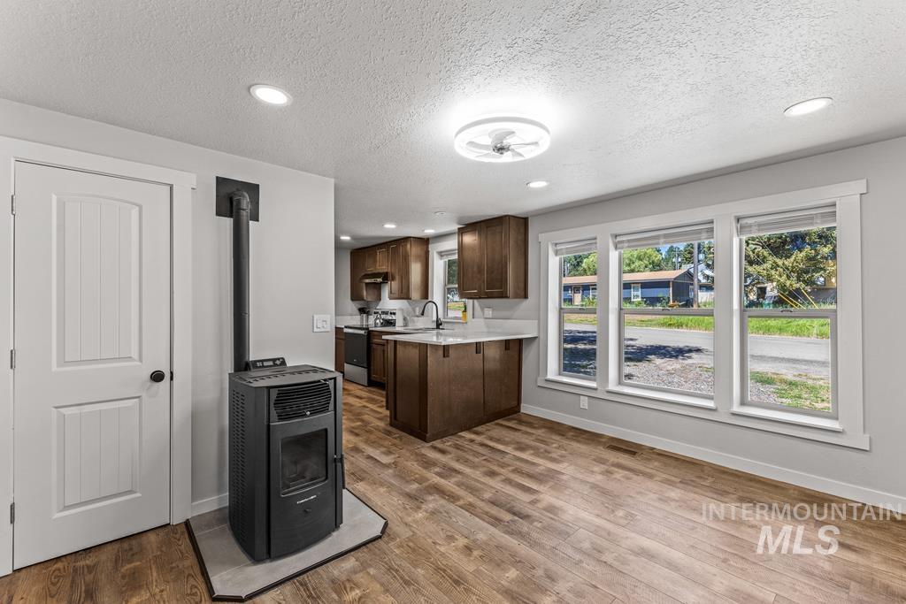 Kitchen featuring dark brown cabinets, a wood stove, recessed lighting, electric stove, and light wood-style flooring