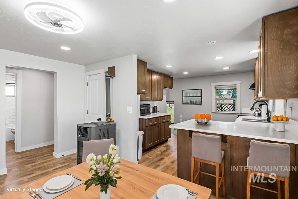 Kitchen featuring a peninsula, a breakfast bar, light wood-type flooring, brown cabinetry, and recessed lighting