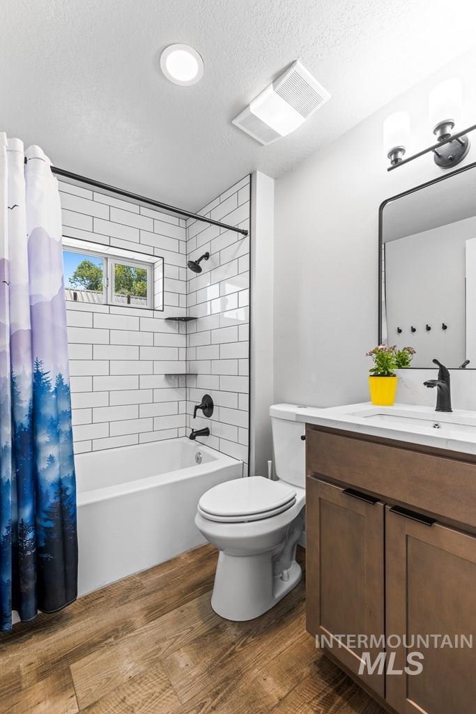 Bathroom with shower / bath combo, dark wood-style floors, vanity, and a textured ceiling