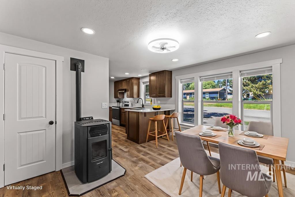 Dining area with a wood stove, a textured ceiling, light wood-style flooring, and recessed lighting