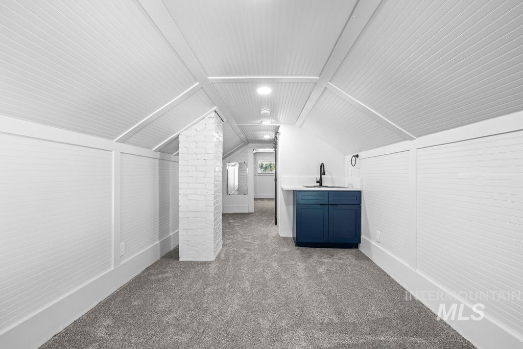 Additional living space with lofted ceiling and dark carpet