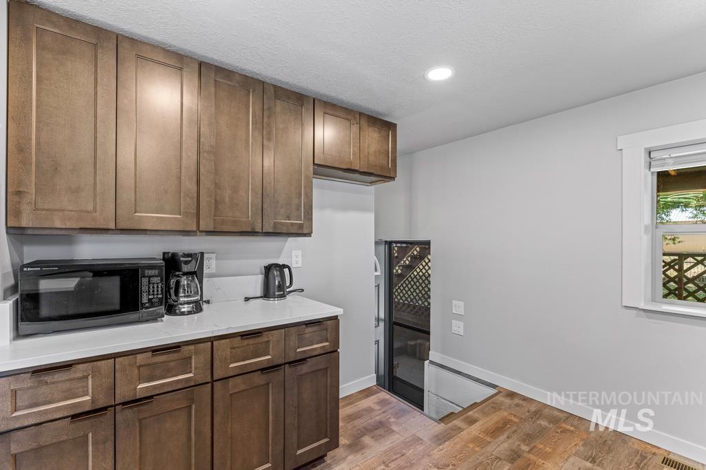 Kitchen featuring dark wood-style floors, black microwave, a textured ceiling, light stone countertops, and recessed lighting