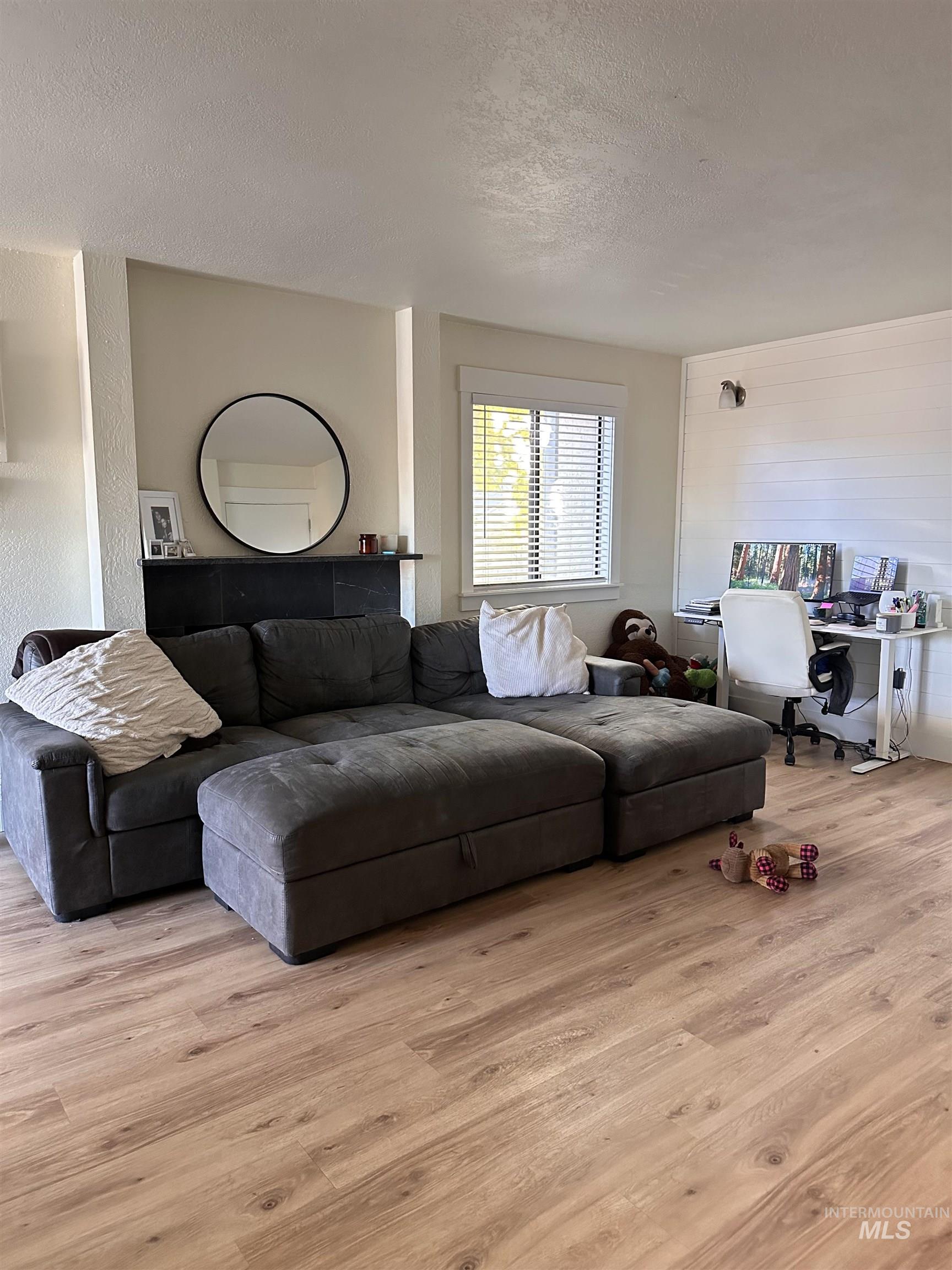 Living area featuring a textured ceiling, light wood finished floors, and a textured wall