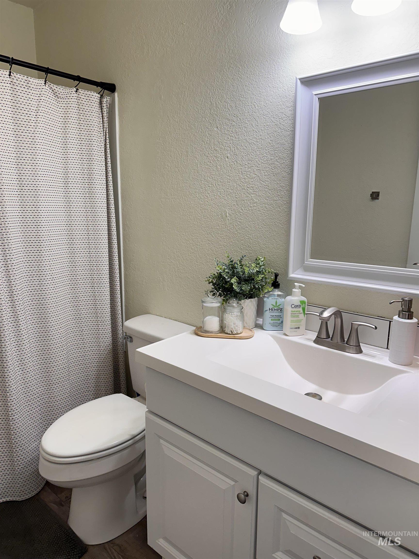 Bathroom featuring vanity, curtained shower, and a textured wall