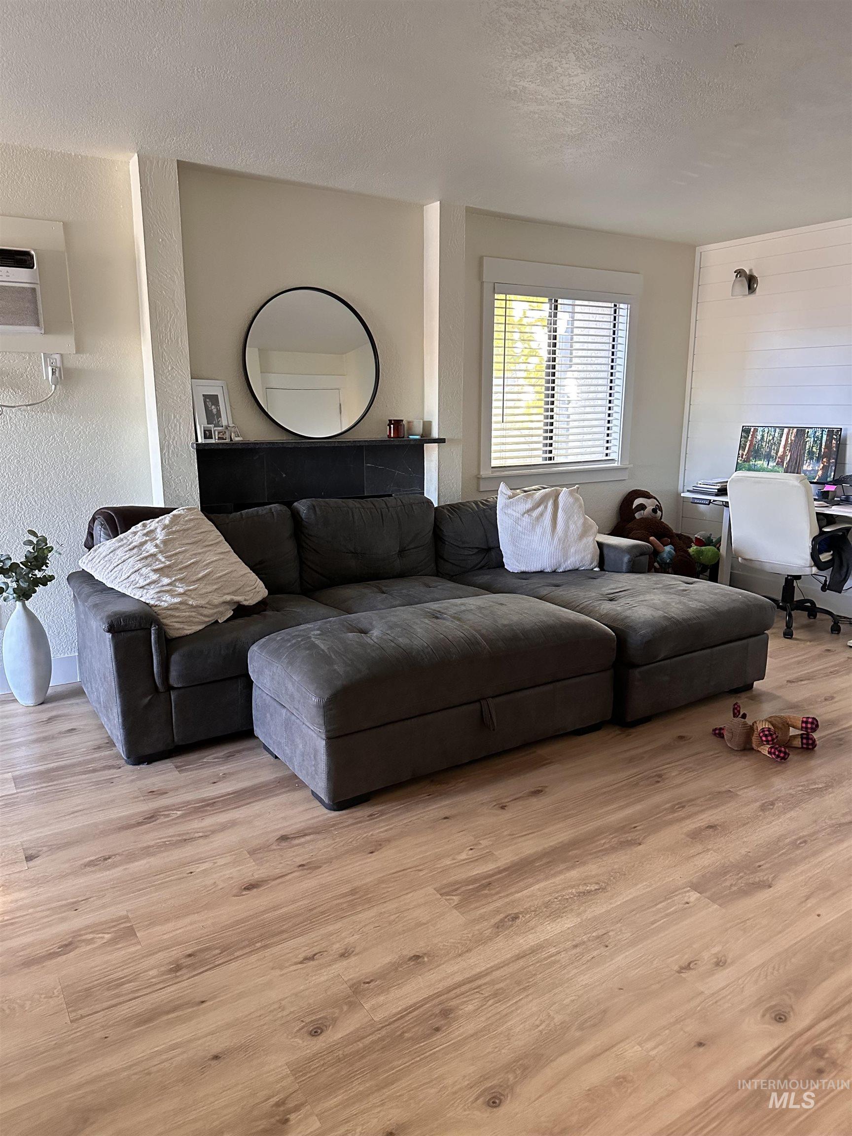 Living room featuring a textured ceiling, a textured wall, light wood-style floors, and an office area