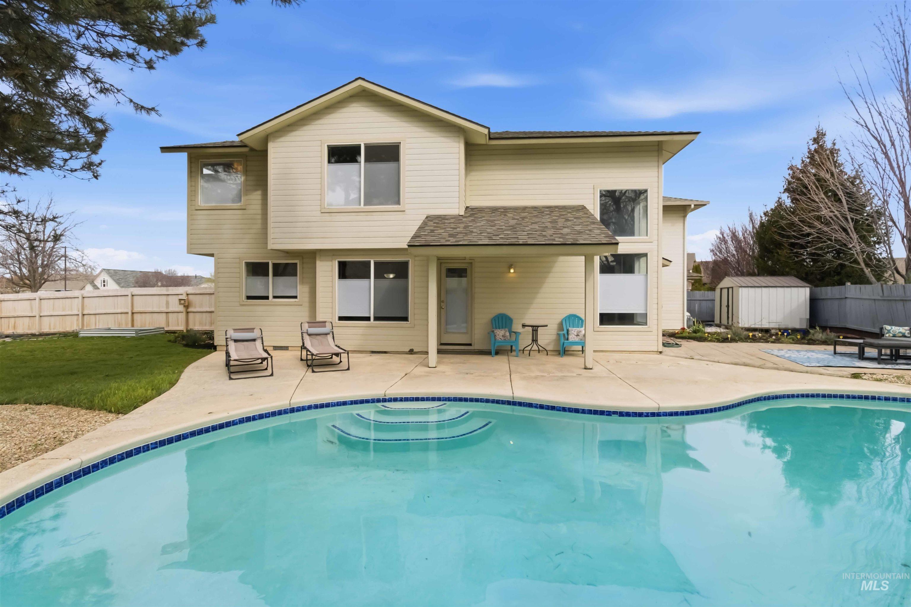 Back of property featuring a fenced backyard, a patio area, roof with shingles, and a storage shed