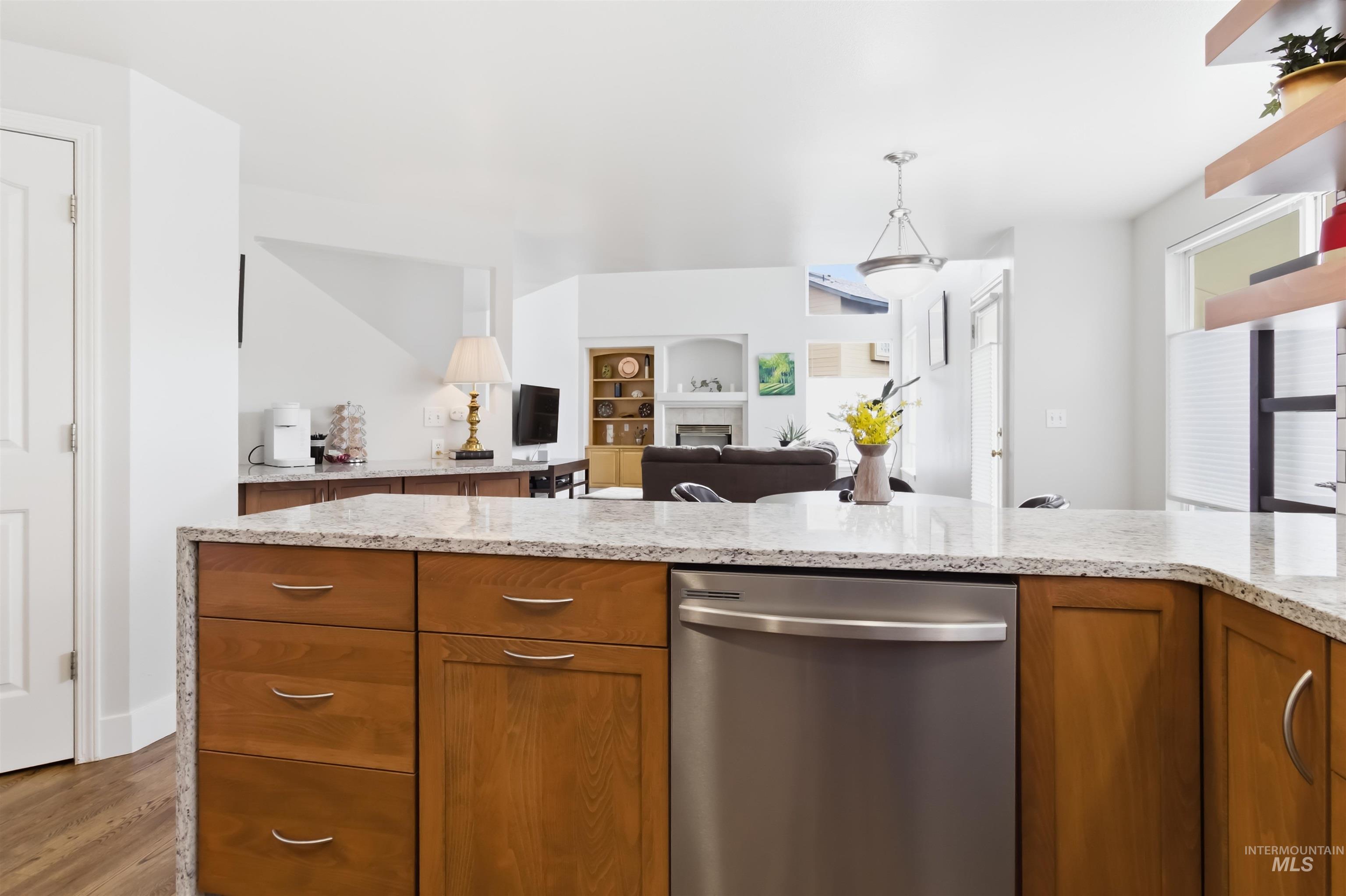 Kitchen featuring stainless steel dishwasher, light stone counters, a fireplace, and open floor plan