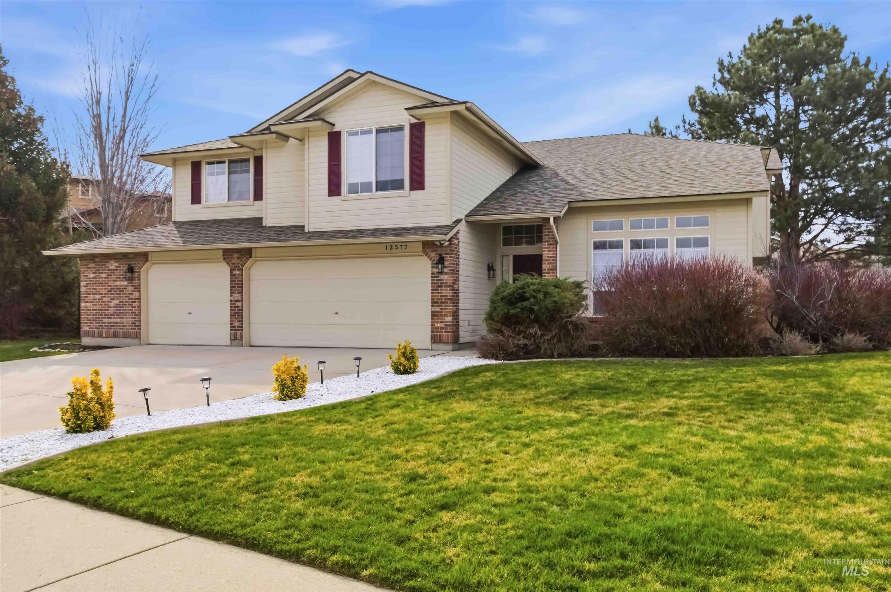 View of front of property with an attached garage, brick siding, a front yard, and concrete driveway