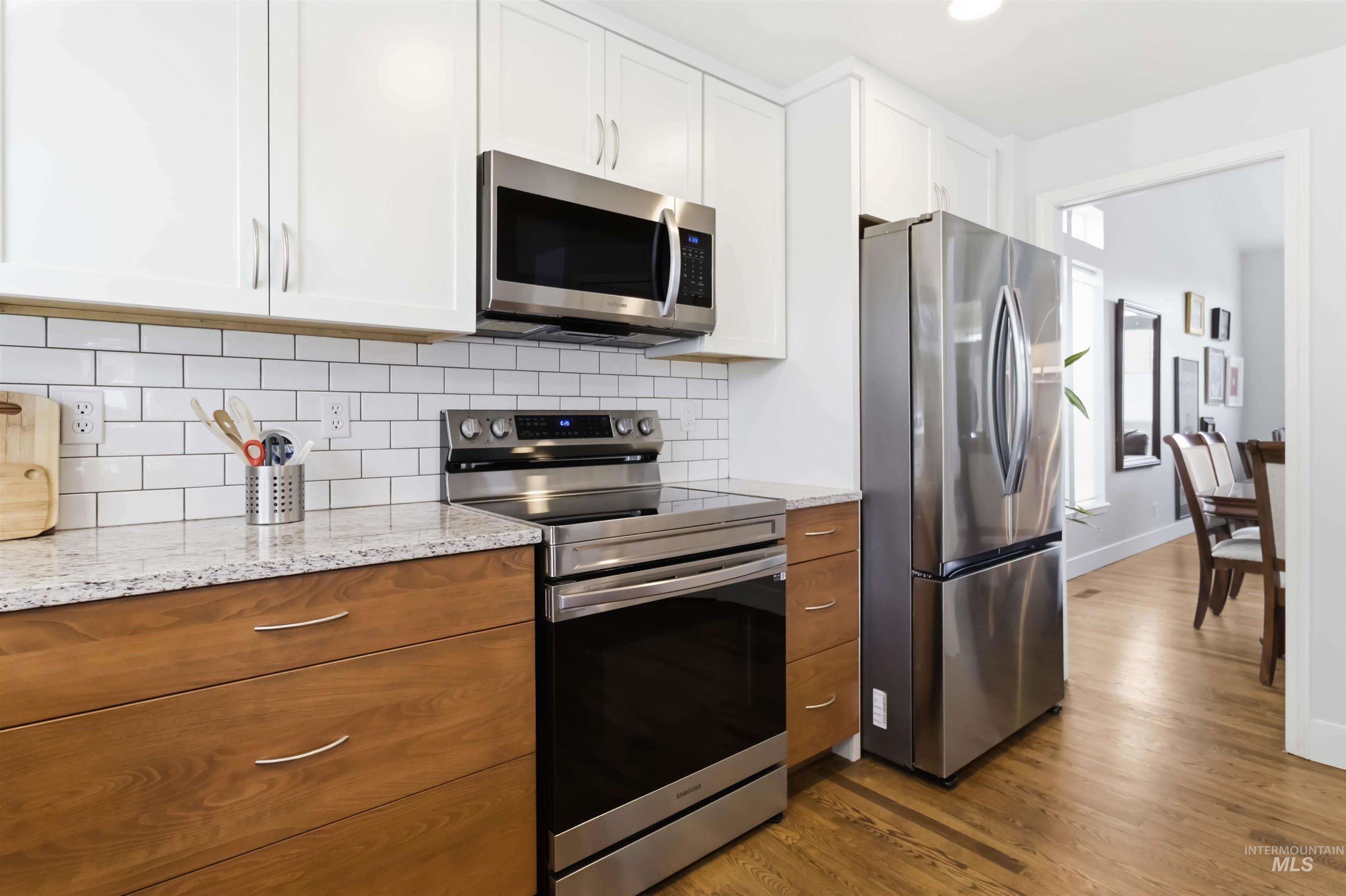 Kitchen featuring stainless steel appliances, light stone countertops, dark wood-style flooring, tasteful backsplash, and recessed lighting