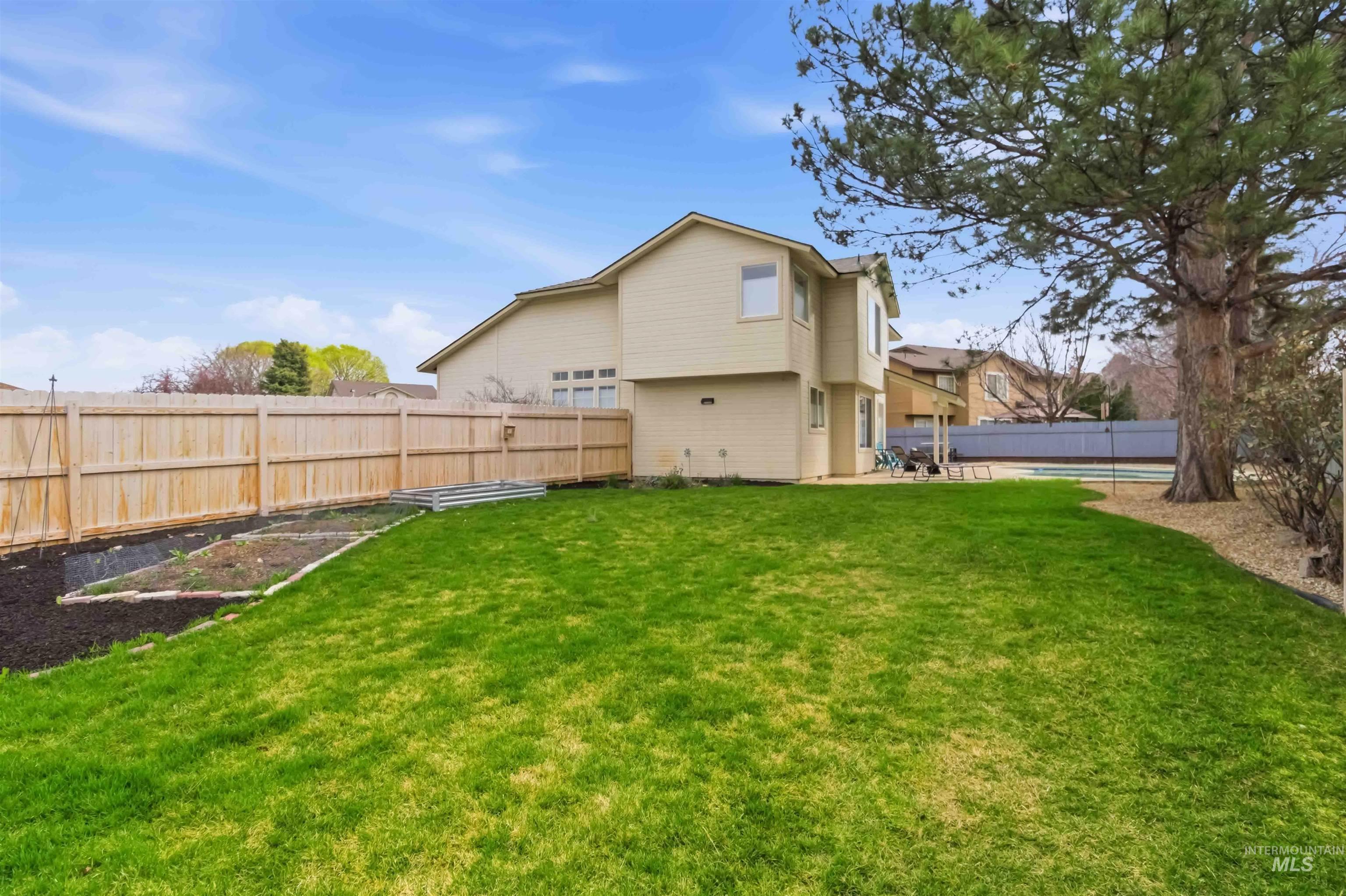 Back of property with a fenced backyard, a swimming pool, and a garden