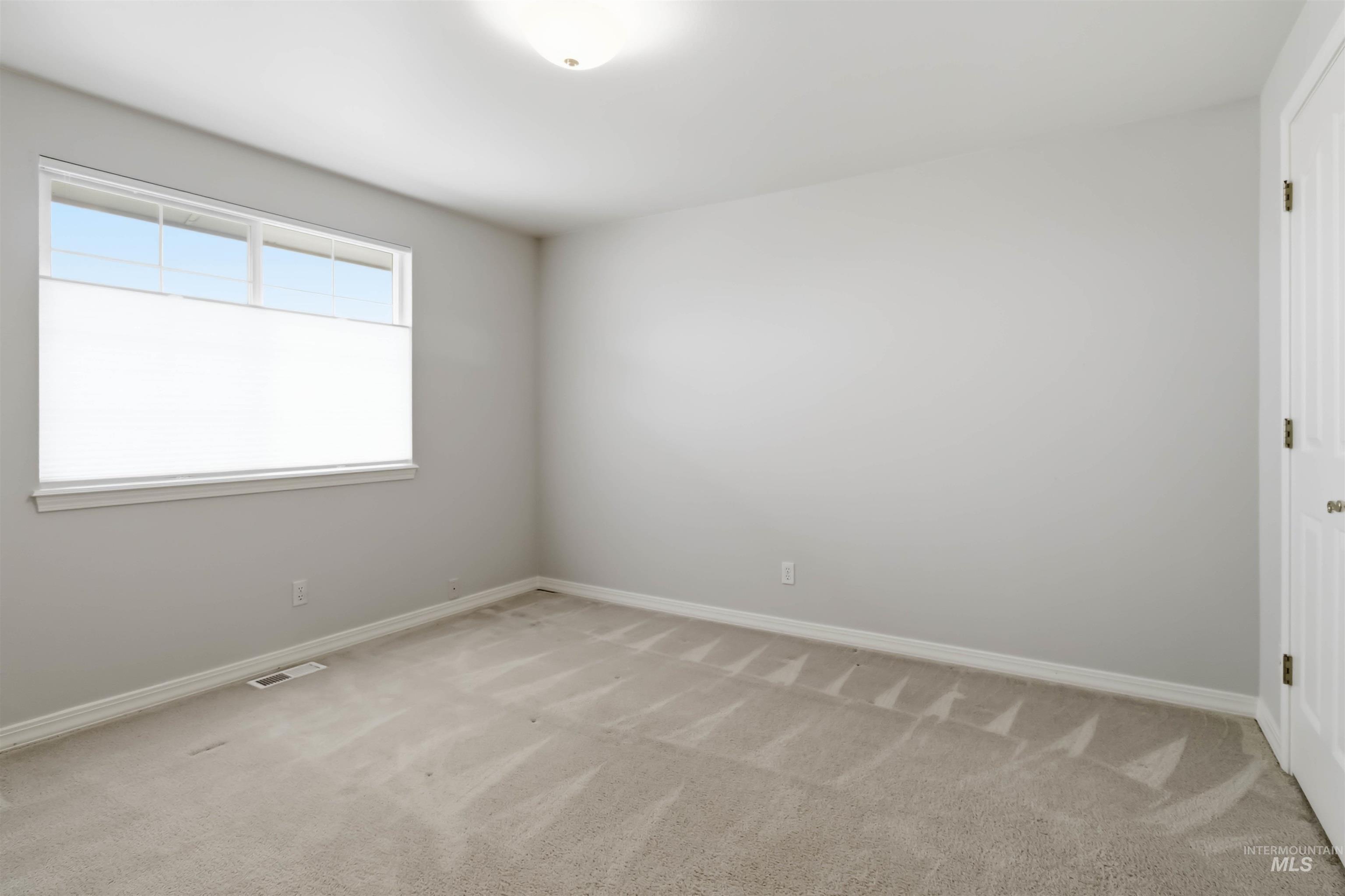 Empty room featuring light colored carpet and baseboards