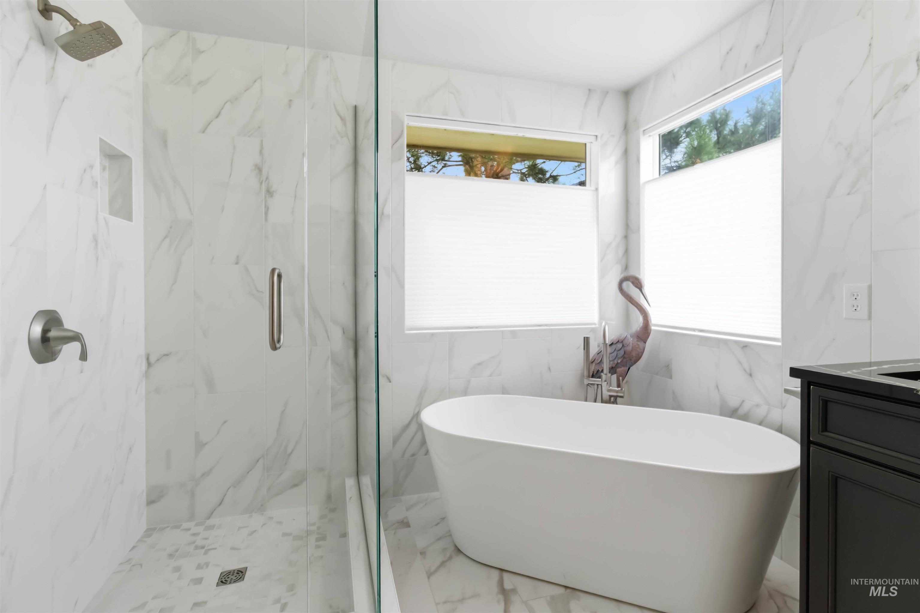 Full bathroom with a marble finish shower, vanity, a soaking tub, light marble finish flooring, and tile walls