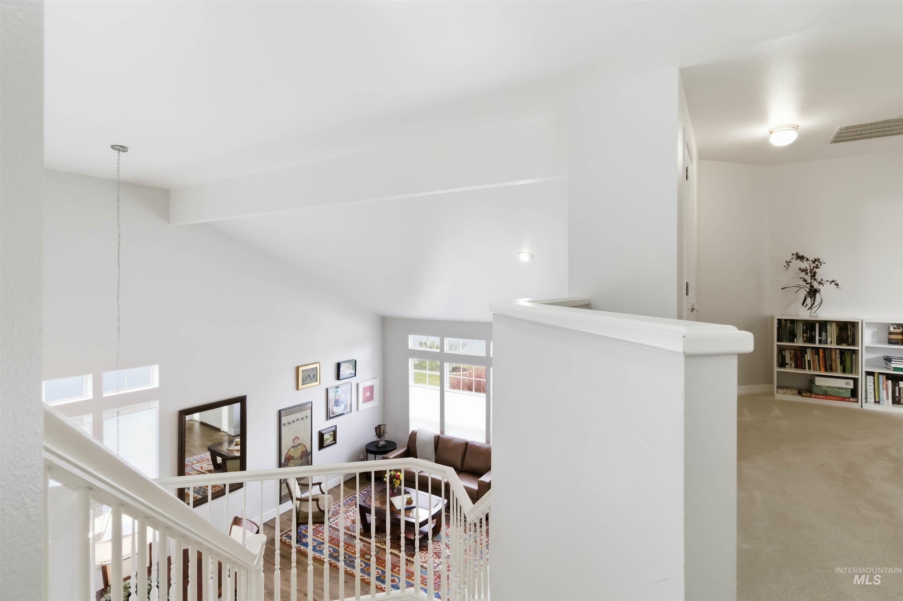 Hallway featuring carpet floors, beam ceiling, and an upstairs landing
