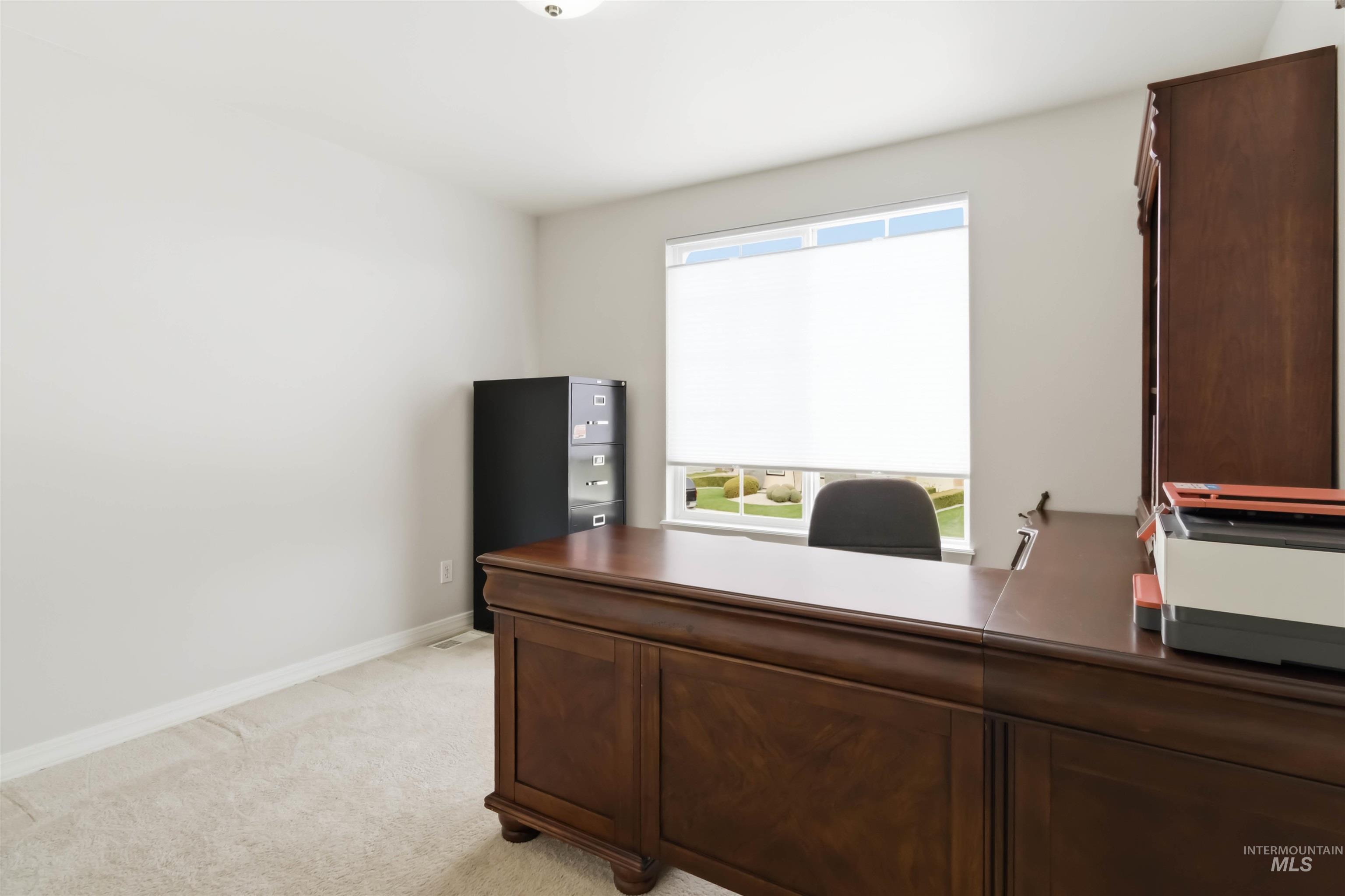 Office space with baseboards and light carpet