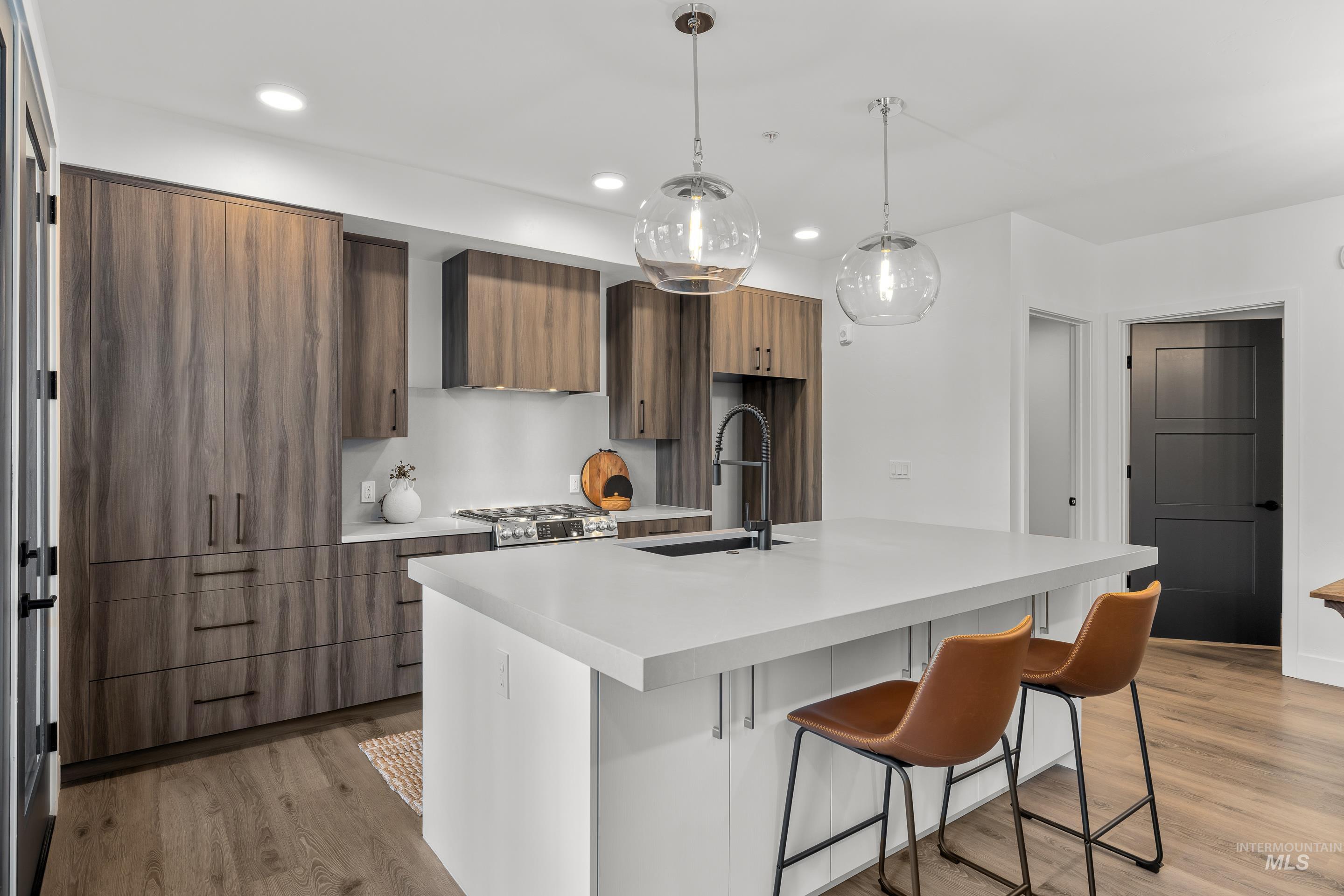 Kitchen with modern cabinets, light wood-type flooring, a breakfast bar area, recessed lighting, and pendant lighting
