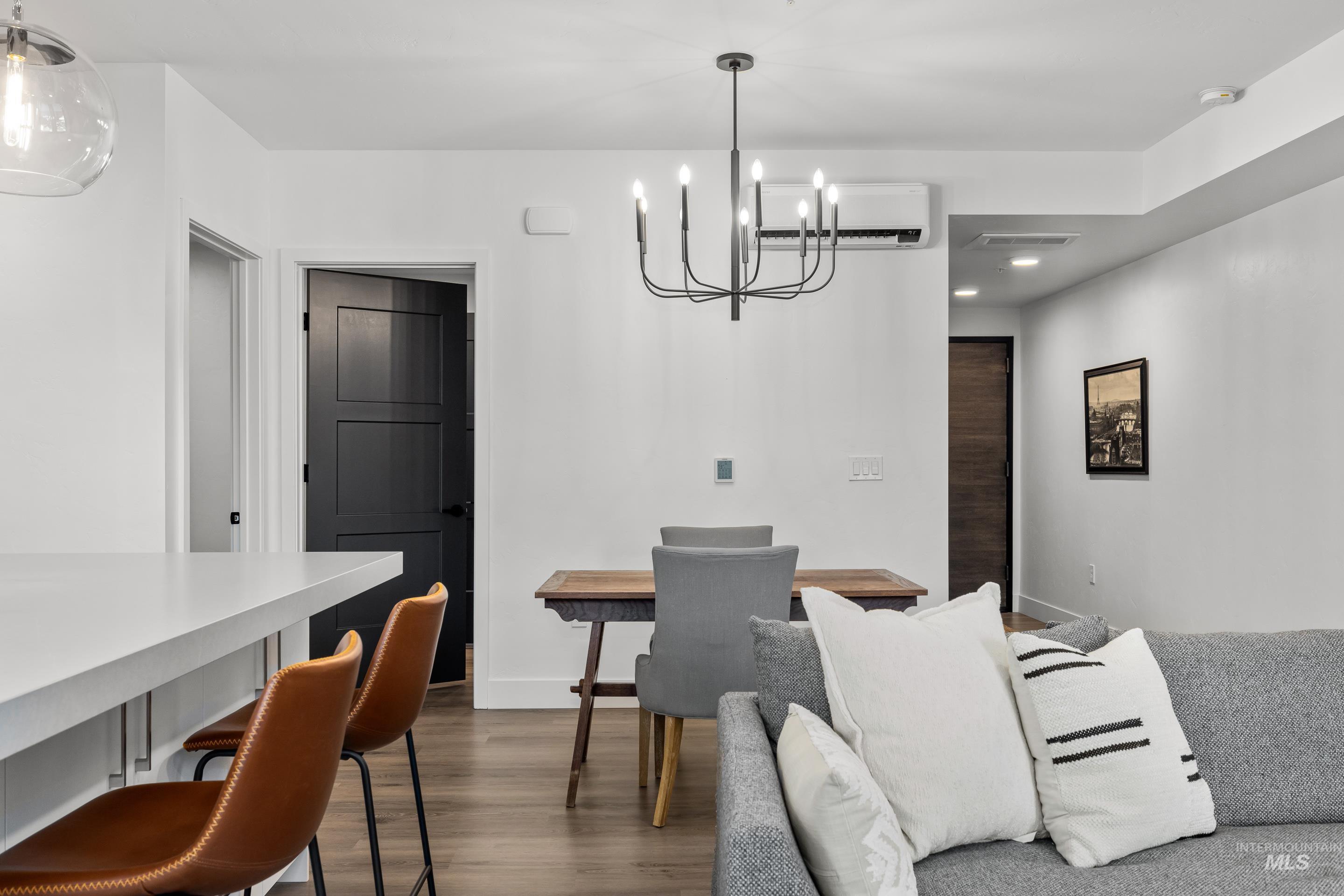 Dining space with dark wood-style flooring, a chandelier, an AC wall unit, and recessed lighting