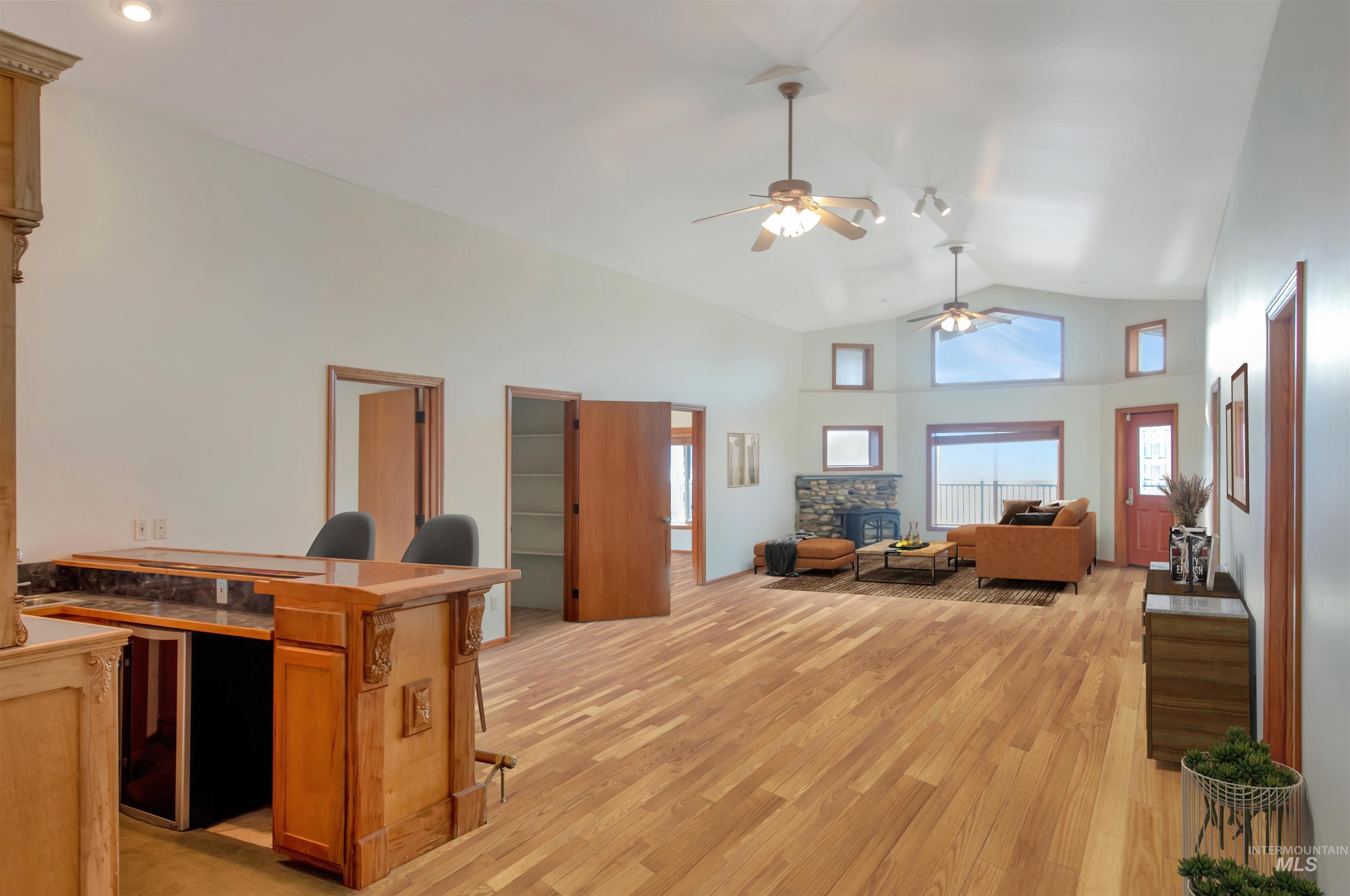 Living room with light wood-type flooring, lofted ceiling, and a ceiling fan. Note that home is vacant and has been virtually staged for the purpose of this photo.