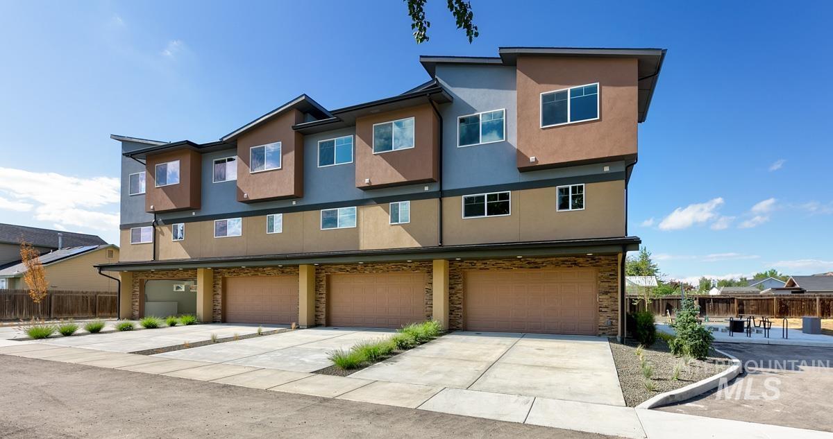 View of front of home with concrete driveway, stucco siding, and a garage