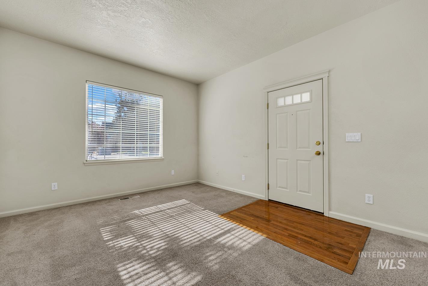 Foyer entrance featuring carpet floors and a textured ceiling