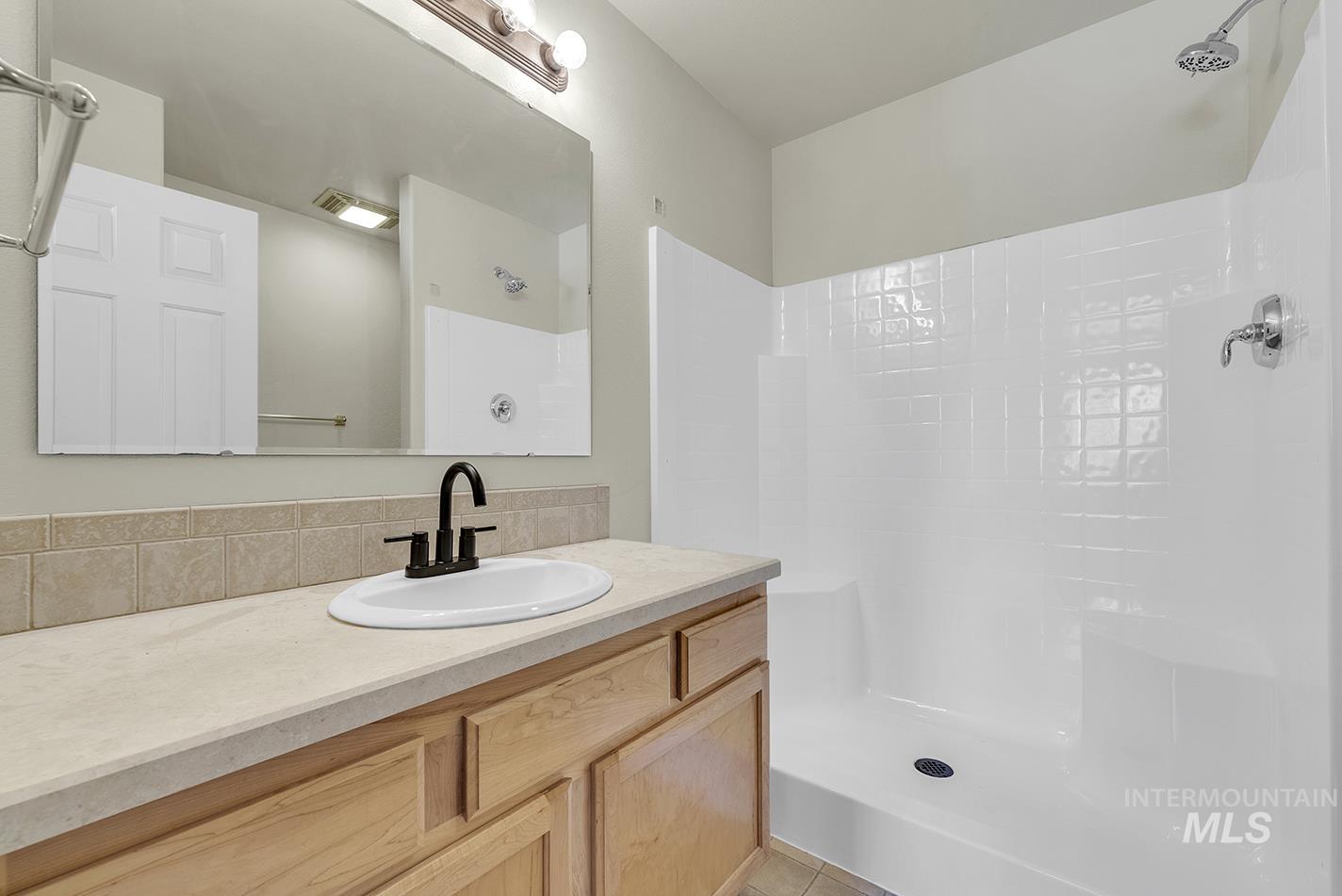Bathroom featuring a shower, vanity, and tile patterned flooring