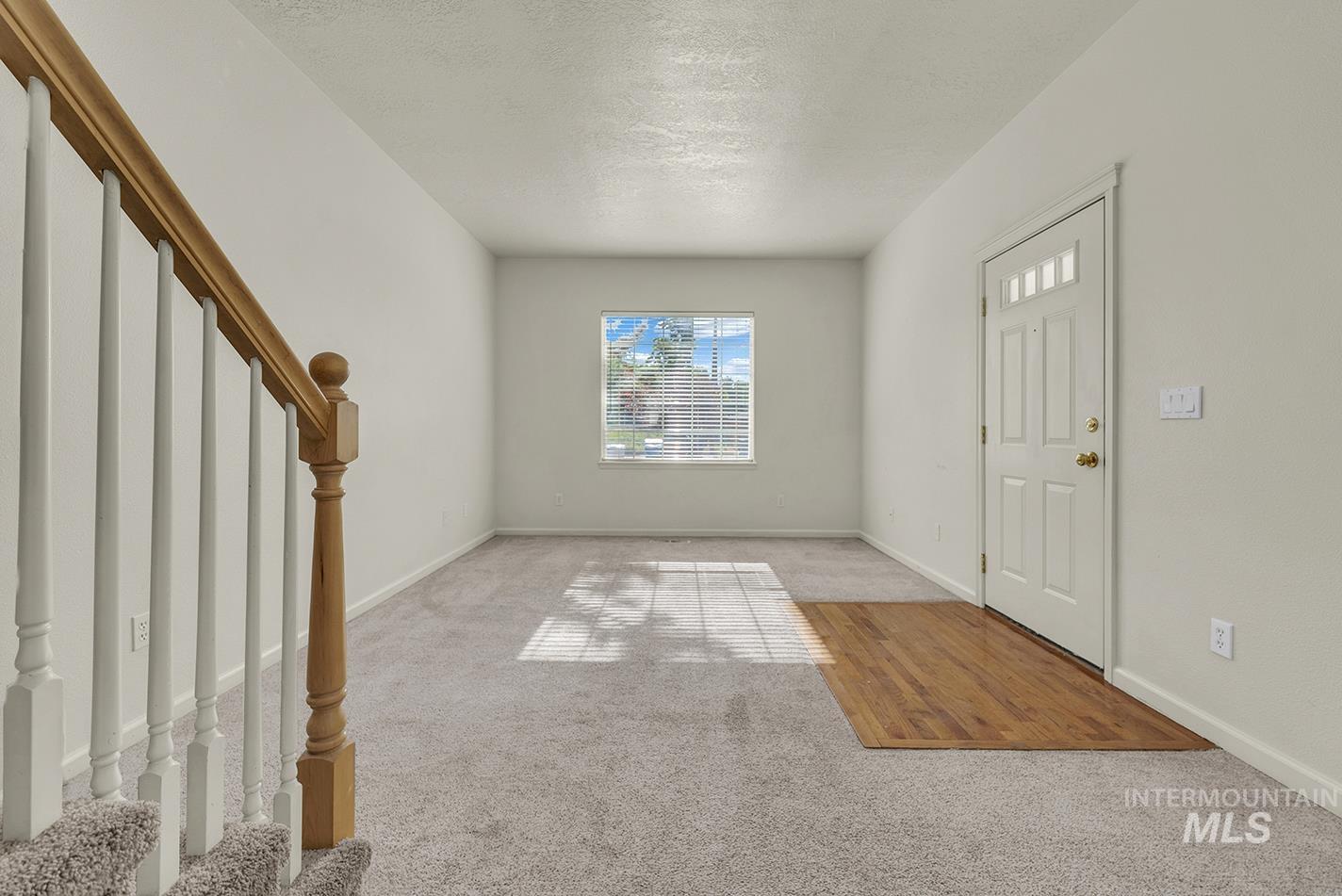 Foyer featuring stairway, carpet floors, and a textured ceiling