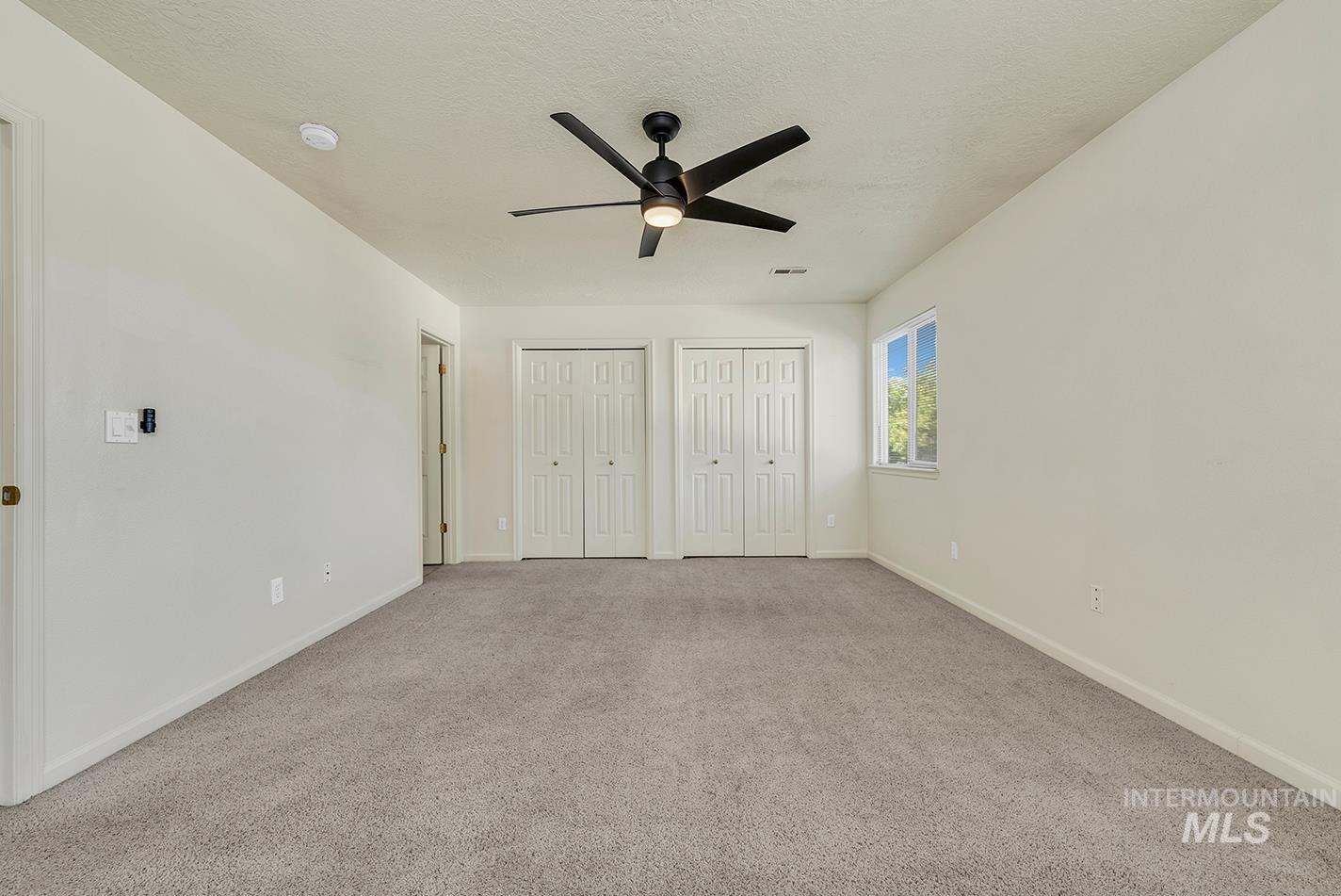 Unfurnished bedroom featuring two closets, carpet flooring, and ceiling fan