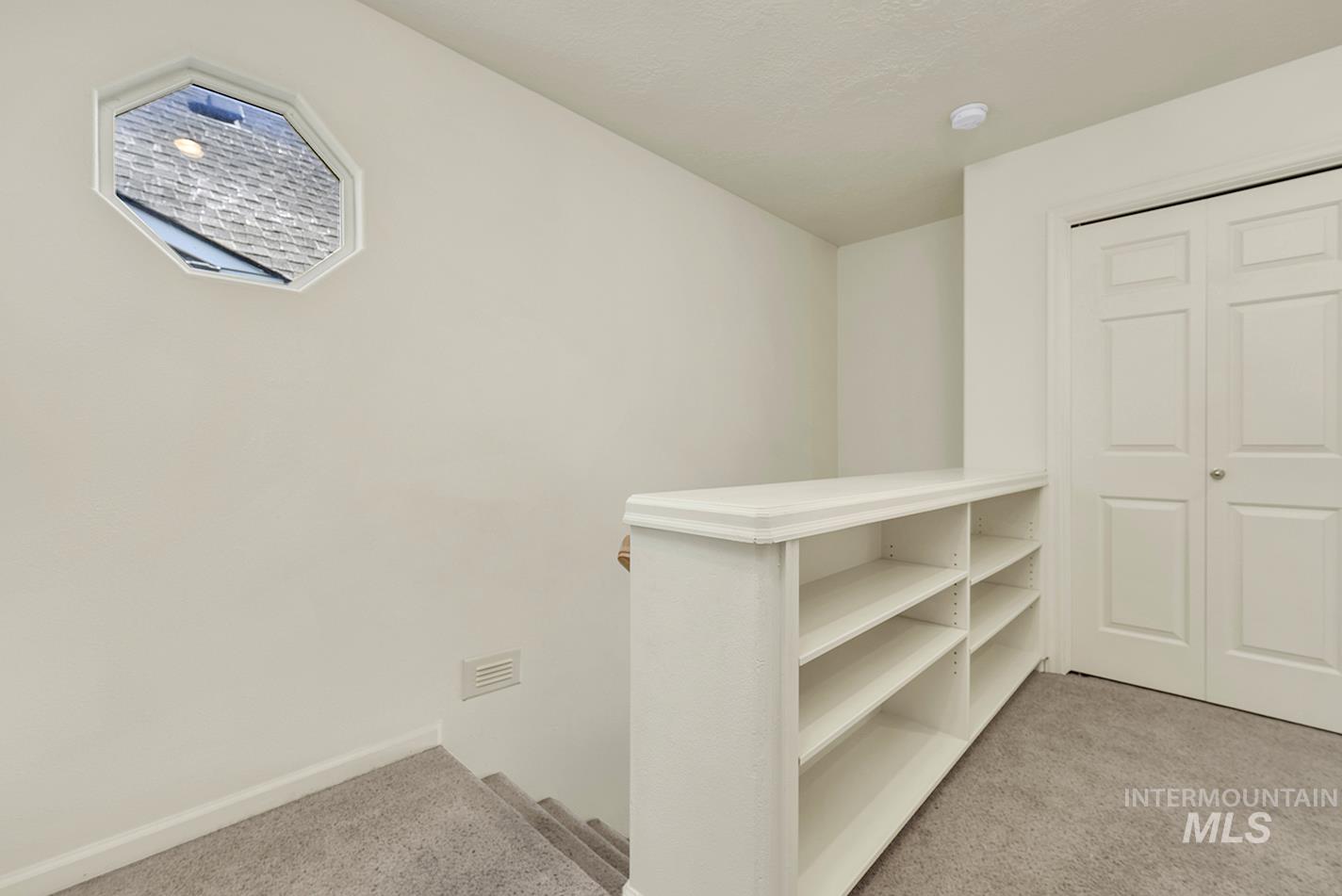 Corridor featuring light colored carpet