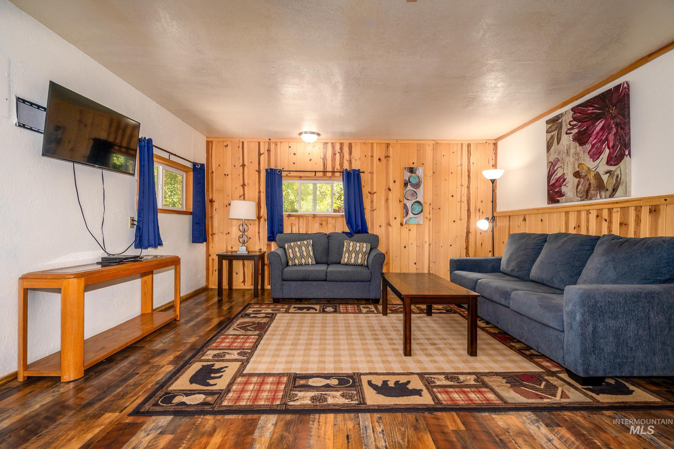 Living area with hardwood / wood-style floors, wooden walls, and a textured ceiling