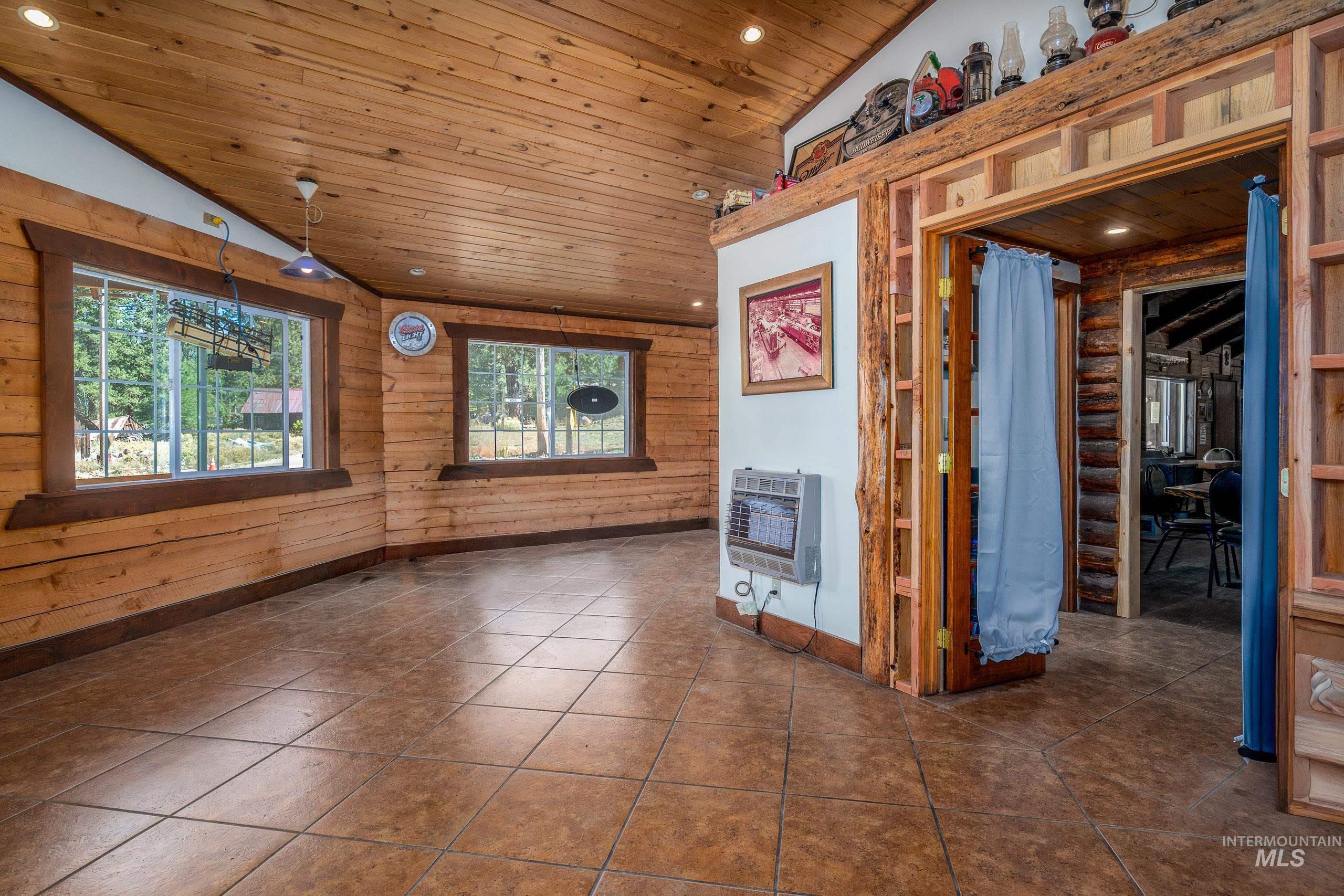 Unfurnished living room featuring vaulted ceiling, heating unit, wooden ceiling, dark tile patterned flooring, and recessed lighting