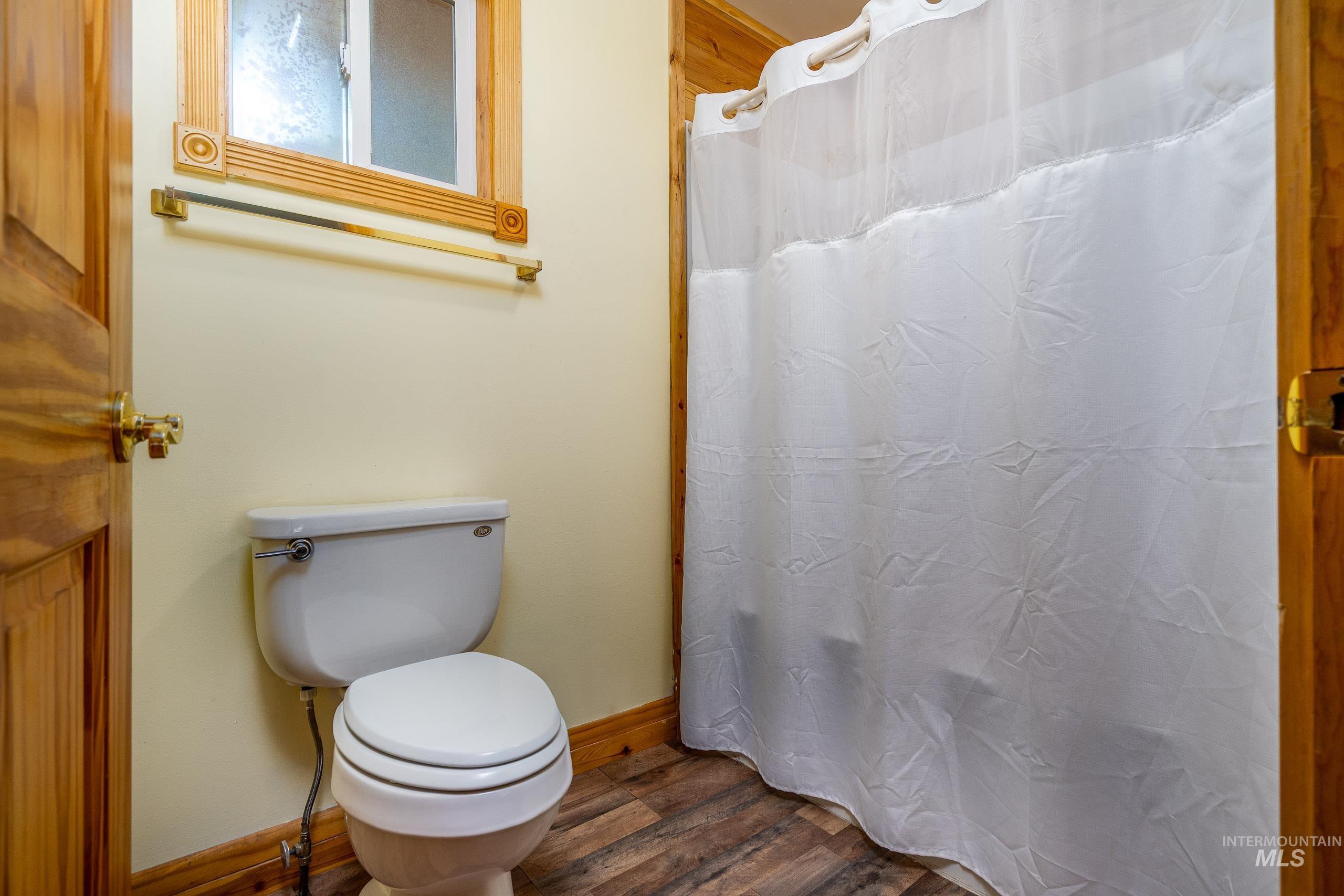 Bathroom featuring curtained shower and dark wood-style floors