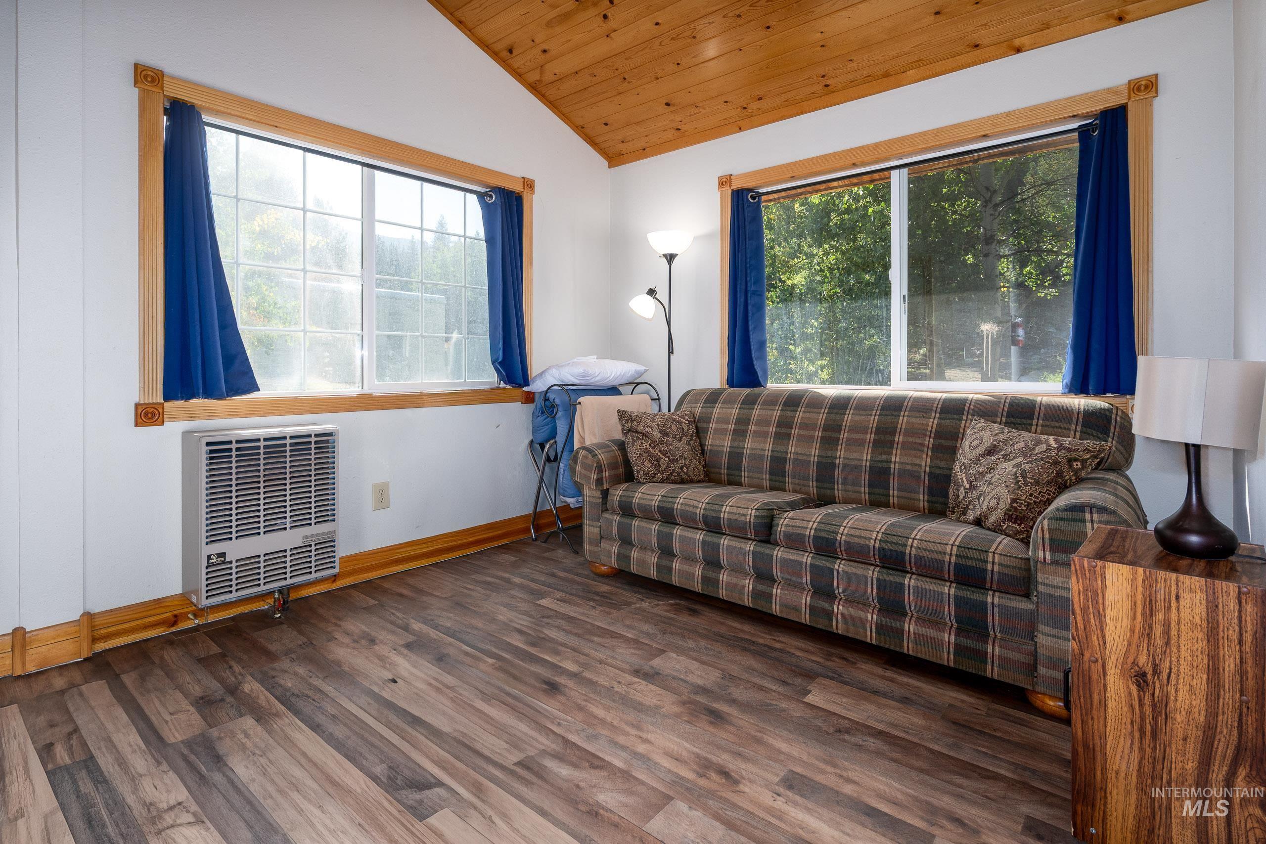 Living area featuring heating unit, wood finished floors, lofted ceiling, and wooden ceiling