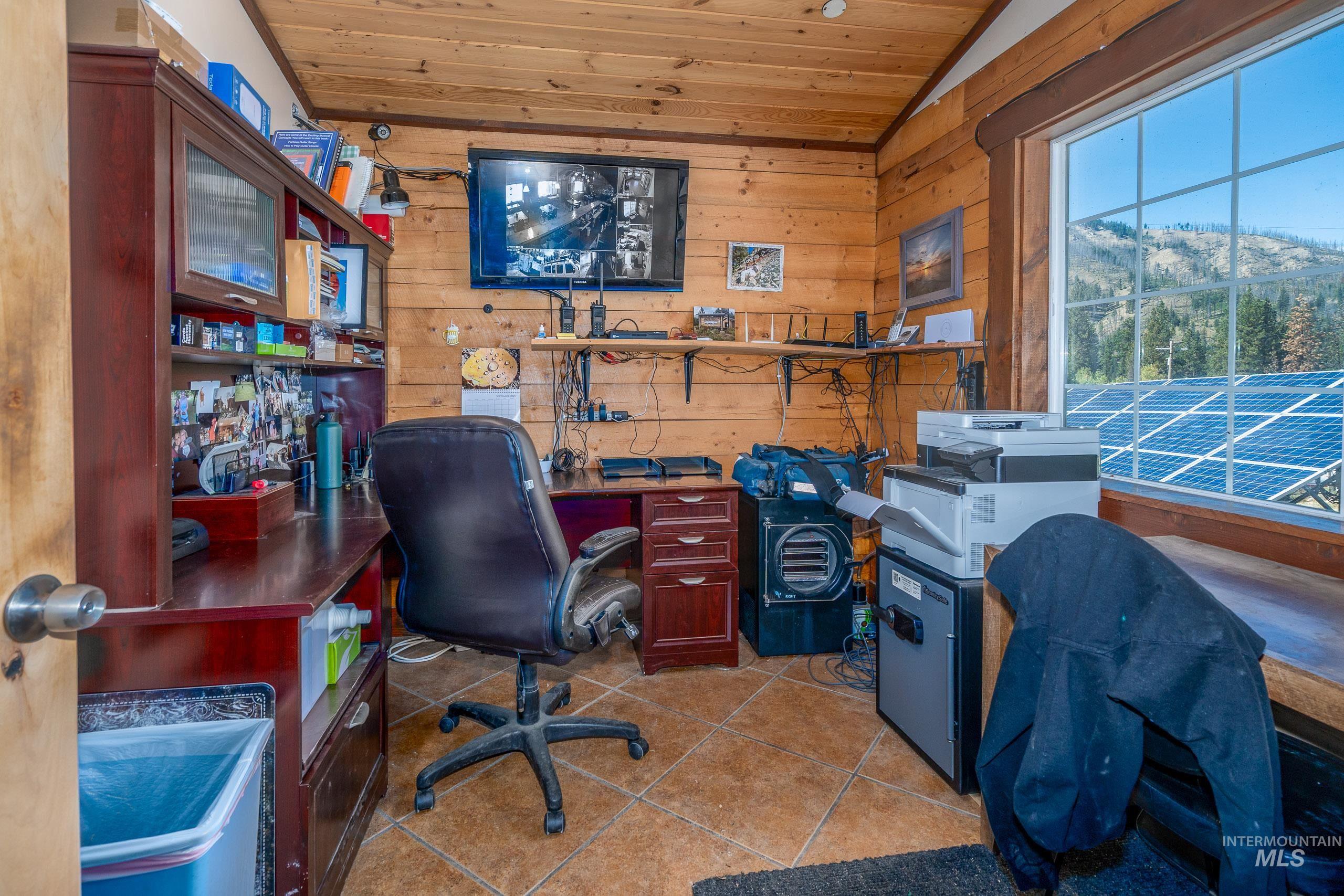 Office with wood walls, light tile patterned floors, wooden ceiling, and lofted ceiling