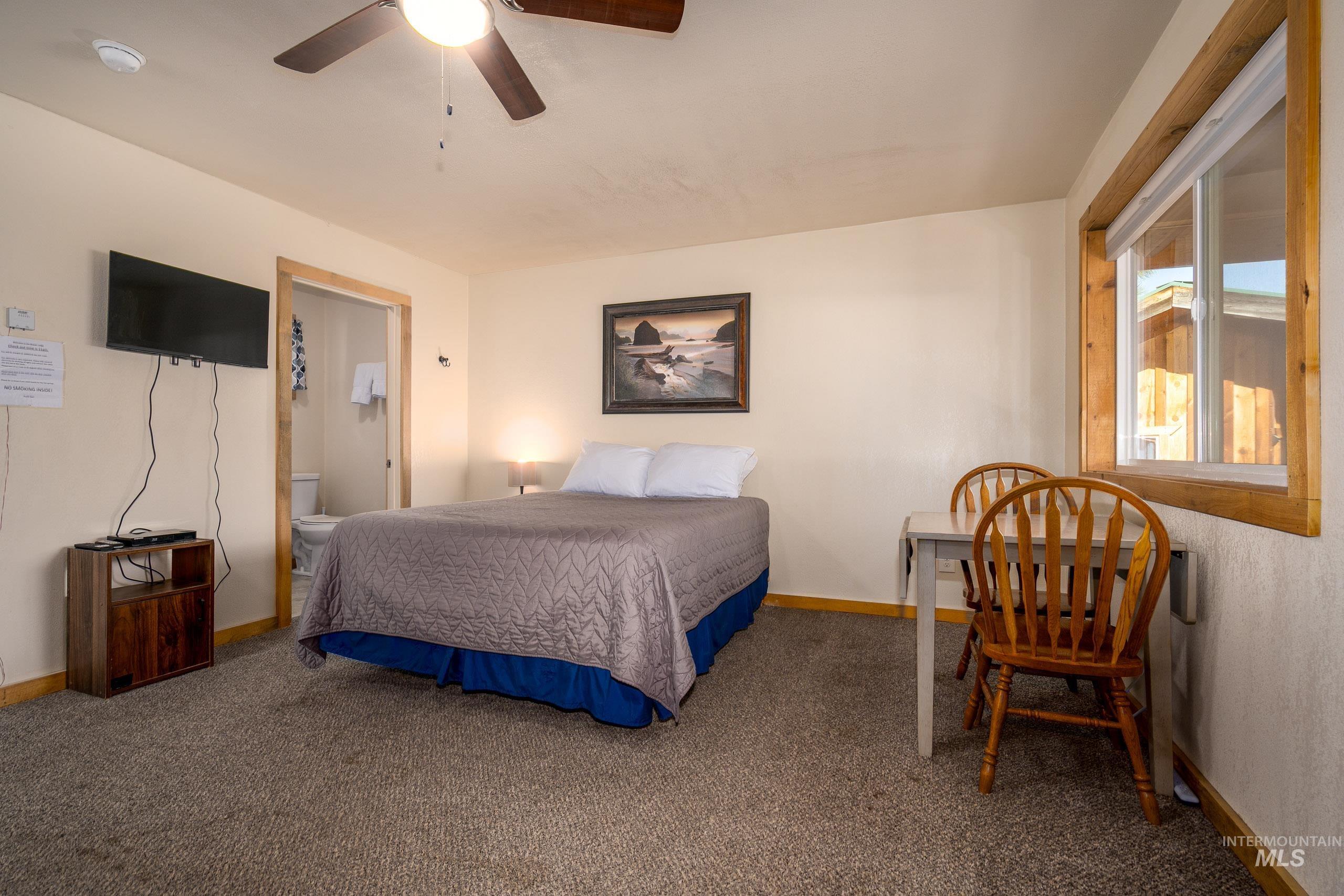 Bedroom featuring carpet floors, ensuite bathroom, and ceiling fan