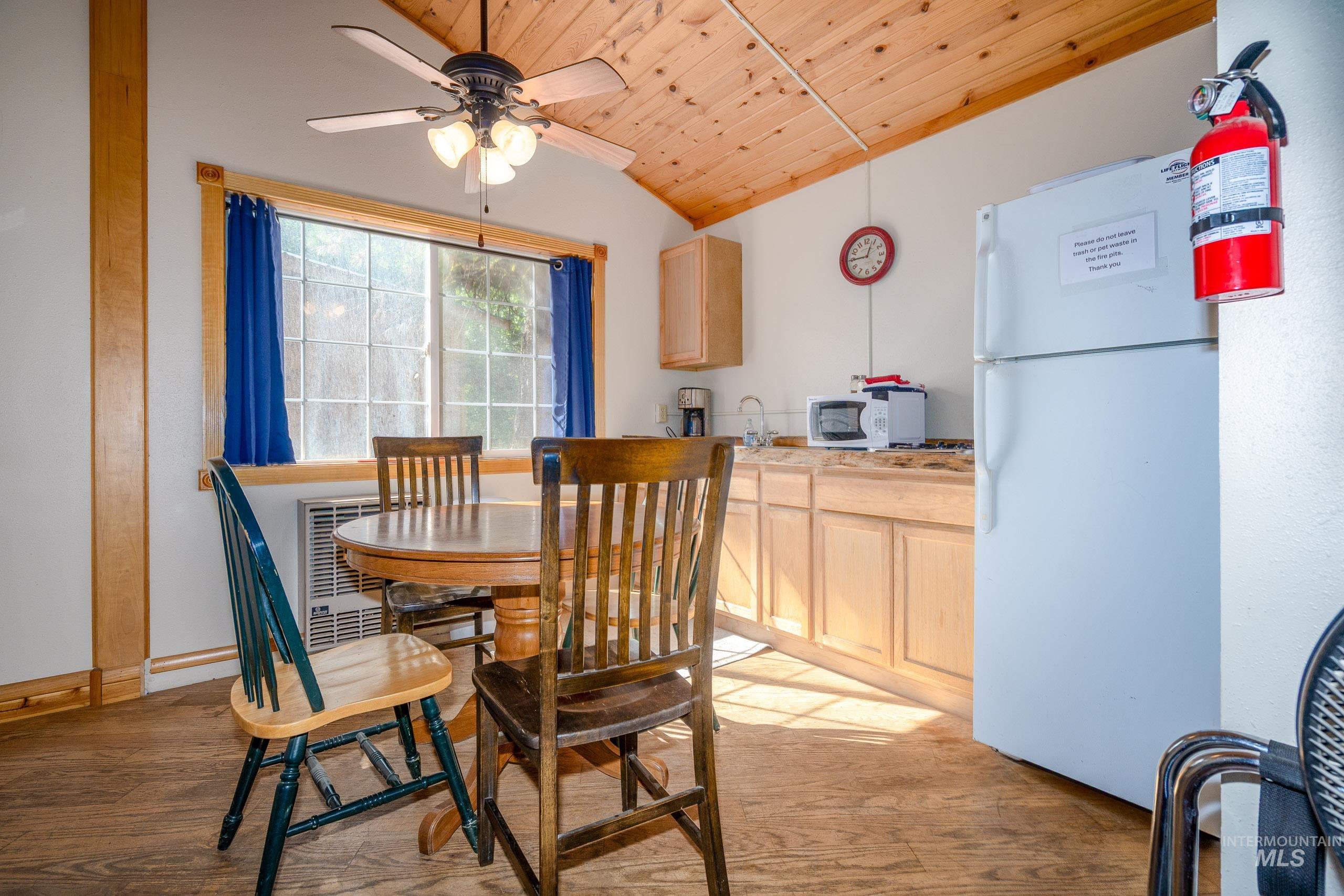 Dining space featuring wooden ceiling, light wood-style flooring, lofted ceiling, a ceiling fan, and heating unit