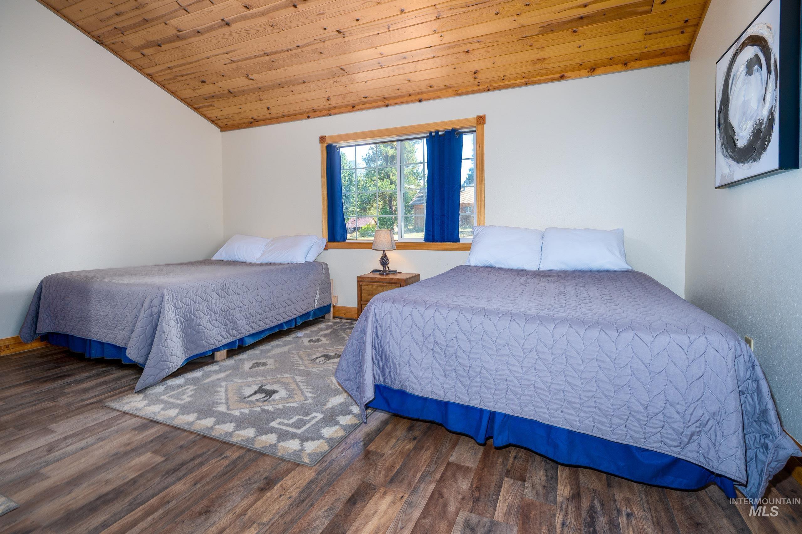 Bedroom with wood ceiling, vaulted ceiling, and wood finished floors