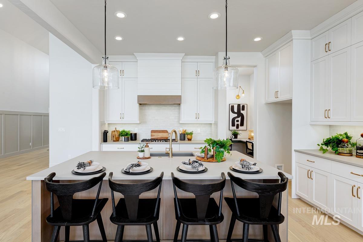 Kitchen featuring a breakfast bar, recessed lighting, decorative light fixtures, white cabinetry, and wainscoting