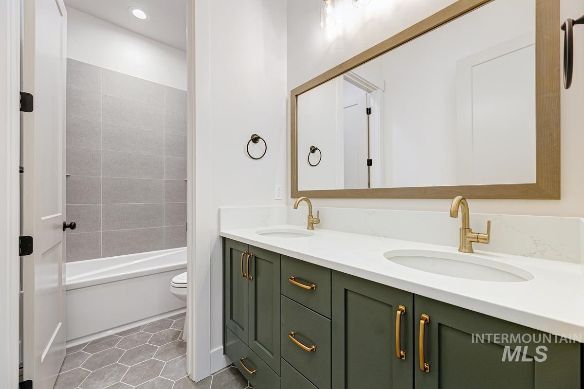 Full bathroom featuring light tile patterned floors, double vanity, shower / bathtub combination, and recessed lighting