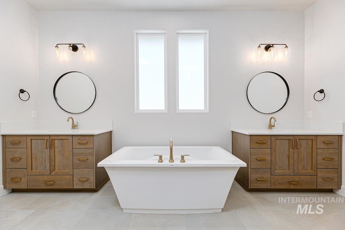 Full bathroom with a soaking tub, two vanities, and light tile patterned flooring