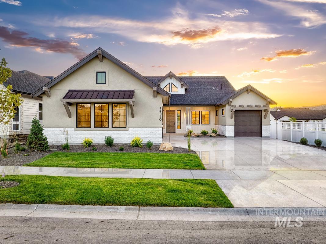 Modern inspired farmhouse with stucco siding, driveway, brick siding, an attached garage, and a standing seam roof