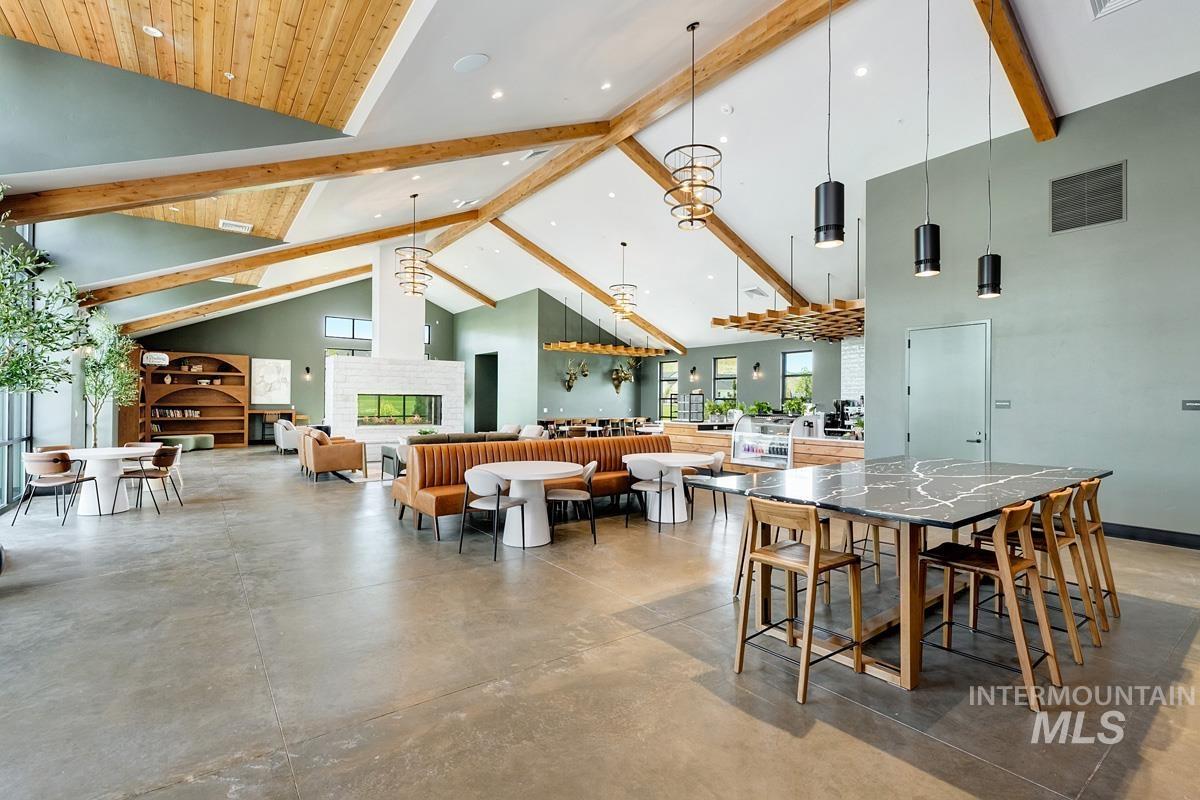 Dining space with high vaulted ceiling, beam ceiling, and concrete floors
