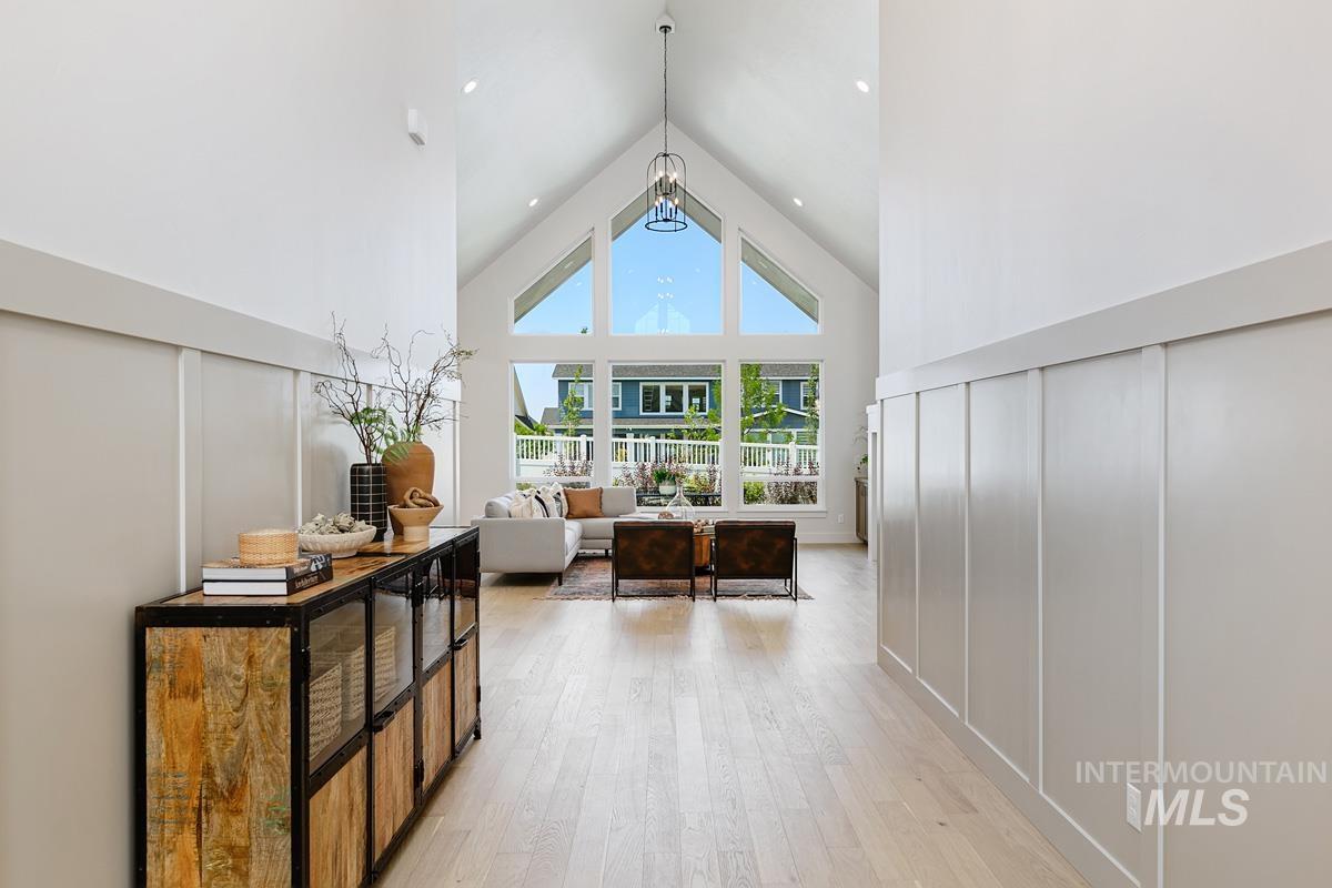 Living area featuring high vaulted ceiling, a decorative wall, light wood finished floors, and a chandelier