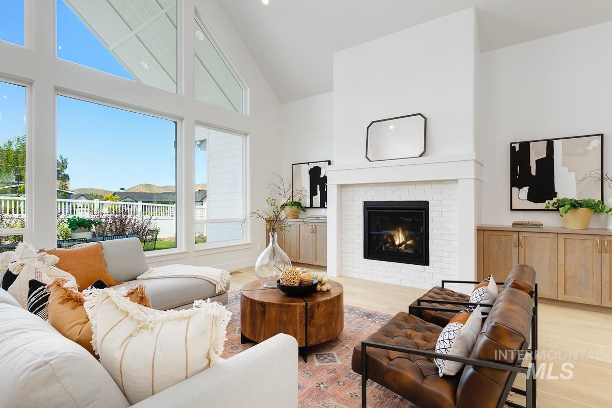 Living room featuring high vaulted ceiling, light wood-style flooring, and a fireplace