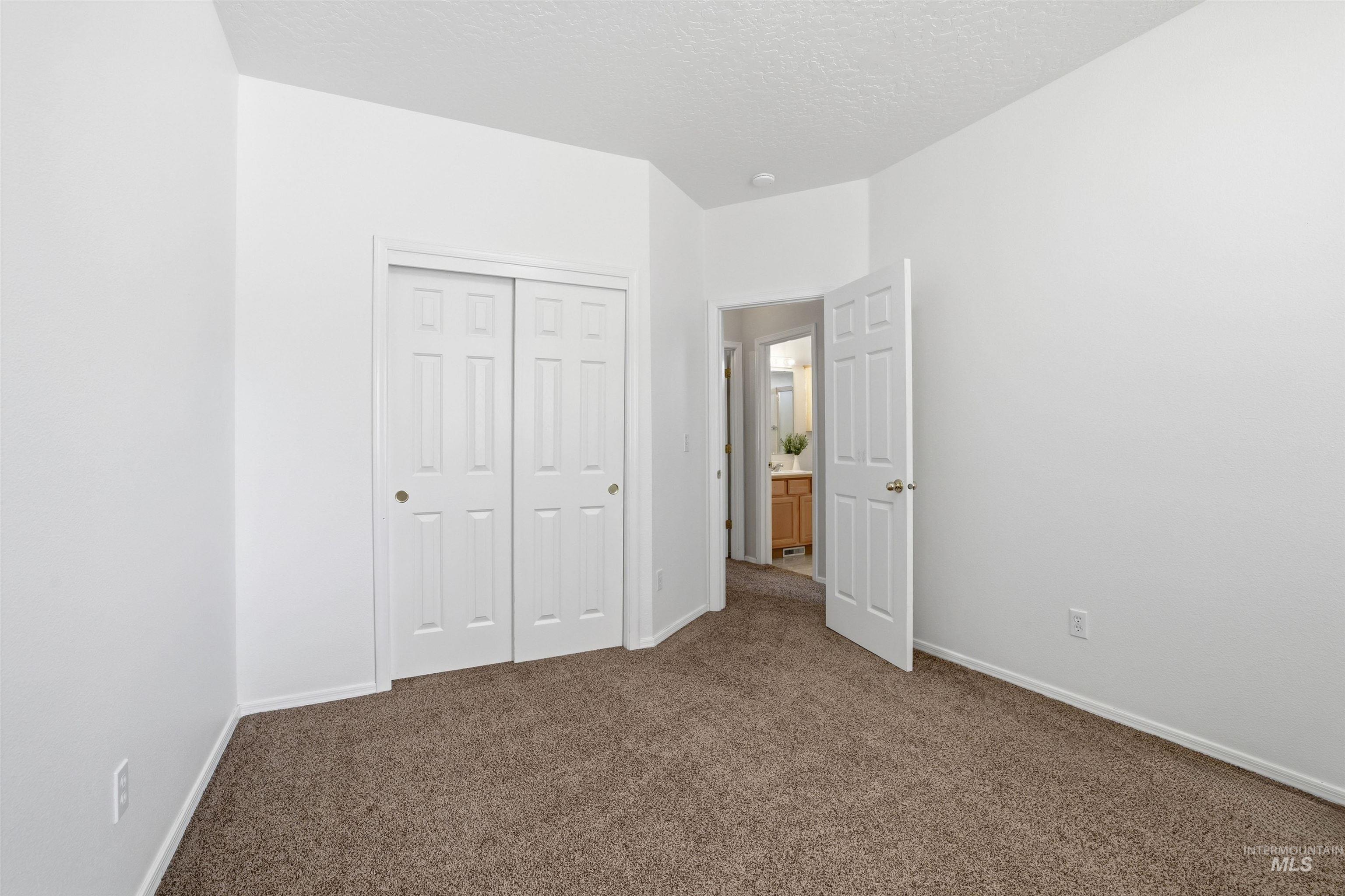 Unfurnished bedroom featuring dark carpet, a closet, and a textured ceiling