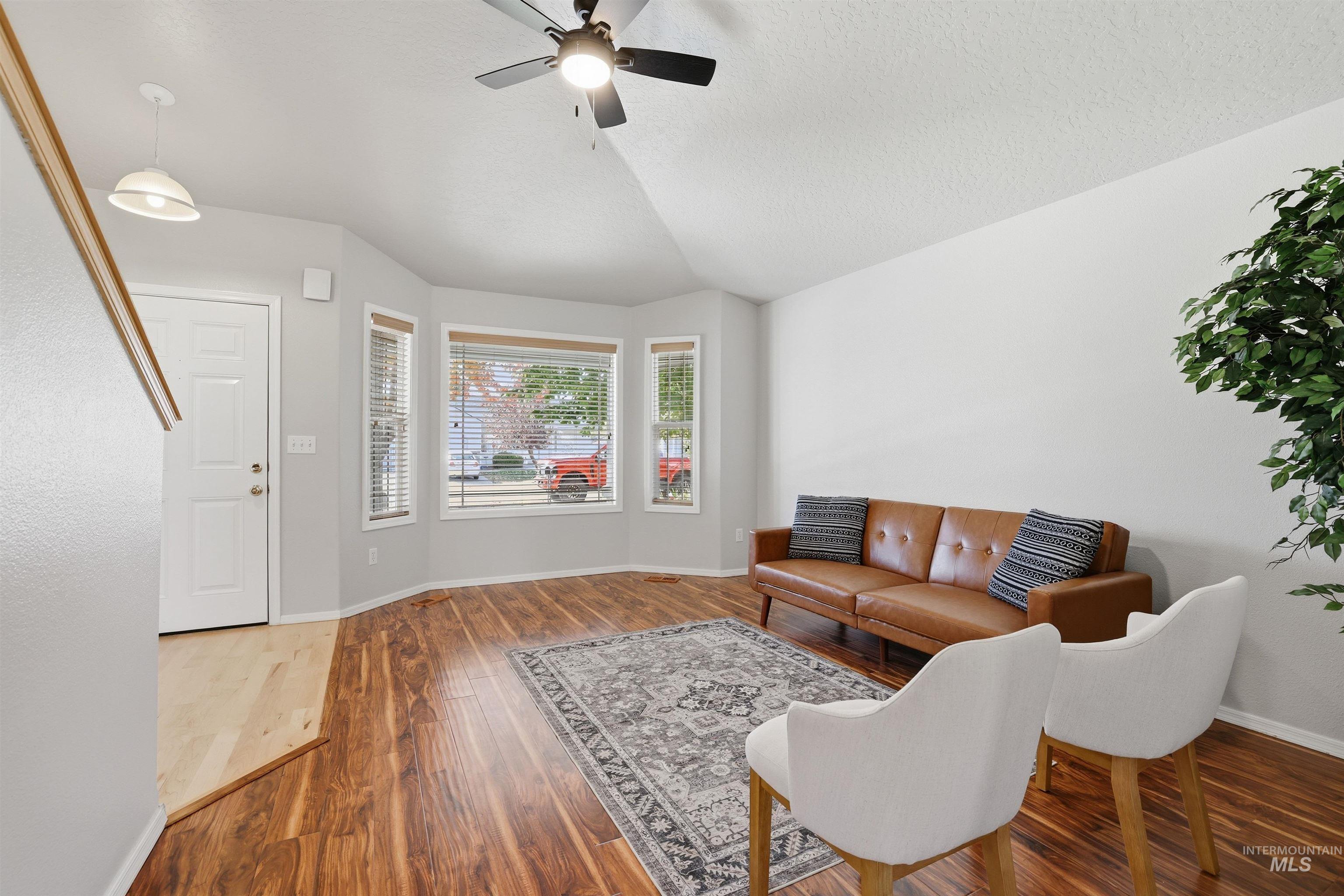 Living area with wood finished floors, vaulted ceiling, ceiling fan, and a textured ceiling