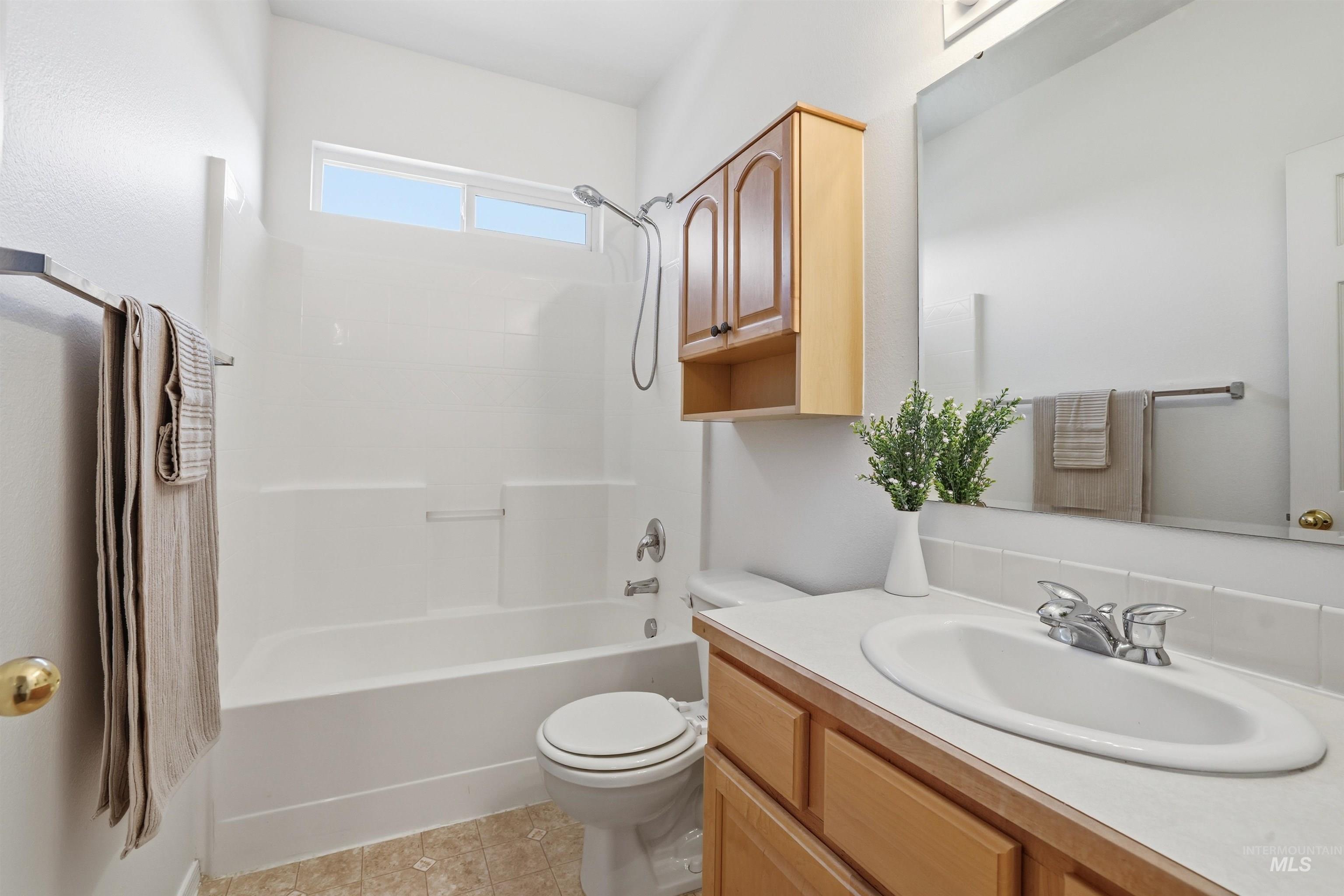 Full bath featuring vanity, shower / bath combination, and light tile patterned floors