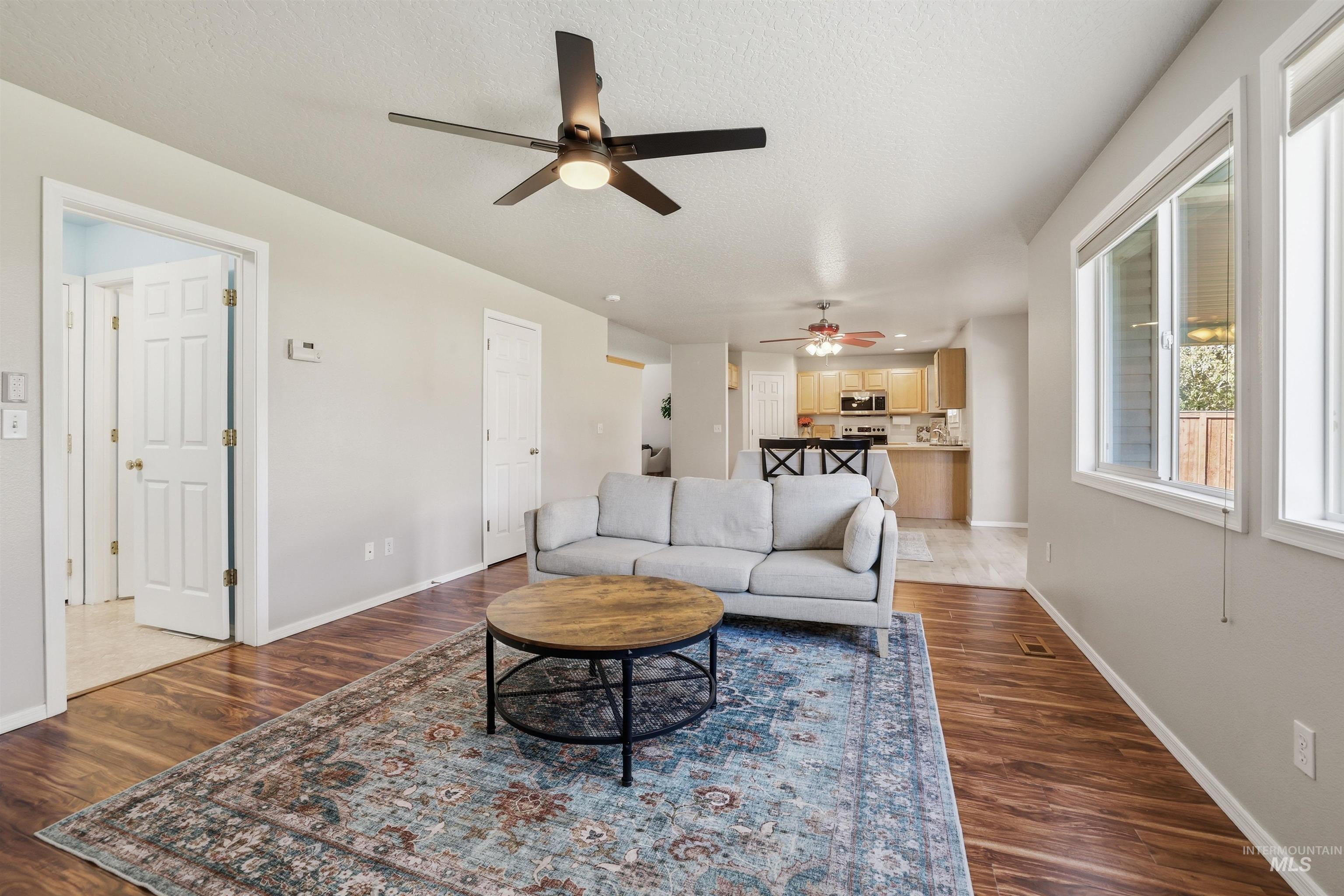 Living area with dark wood-type flooring, a ceiling fan, and a textured ceiling