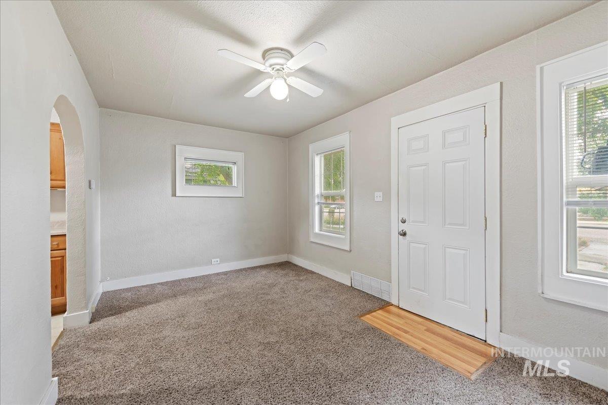 Foyer featuring light carpet, arched walkways, ceiling fan, and a textured wall