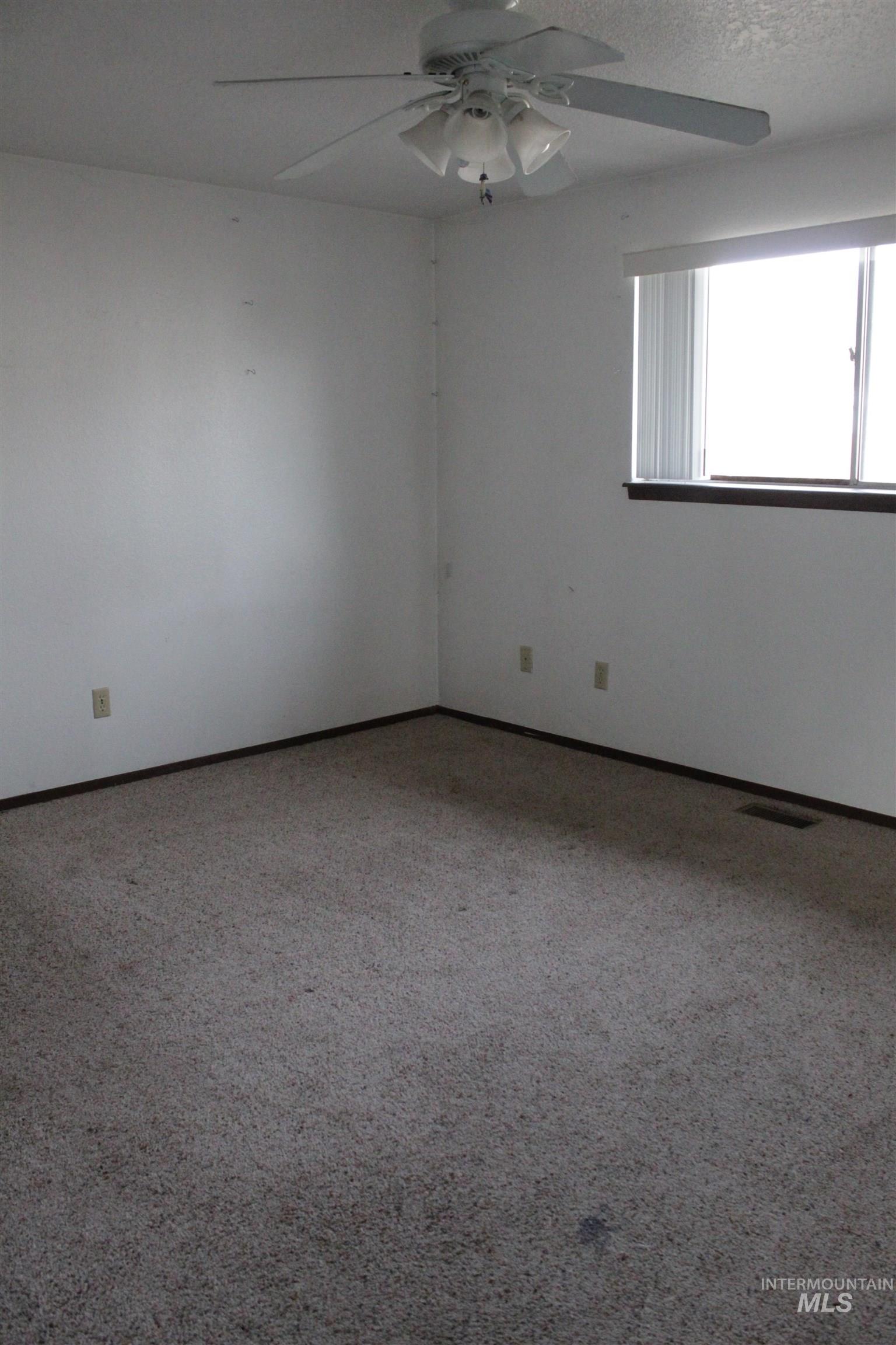 Carpeted empty room featuring ceiling fan and baseboards