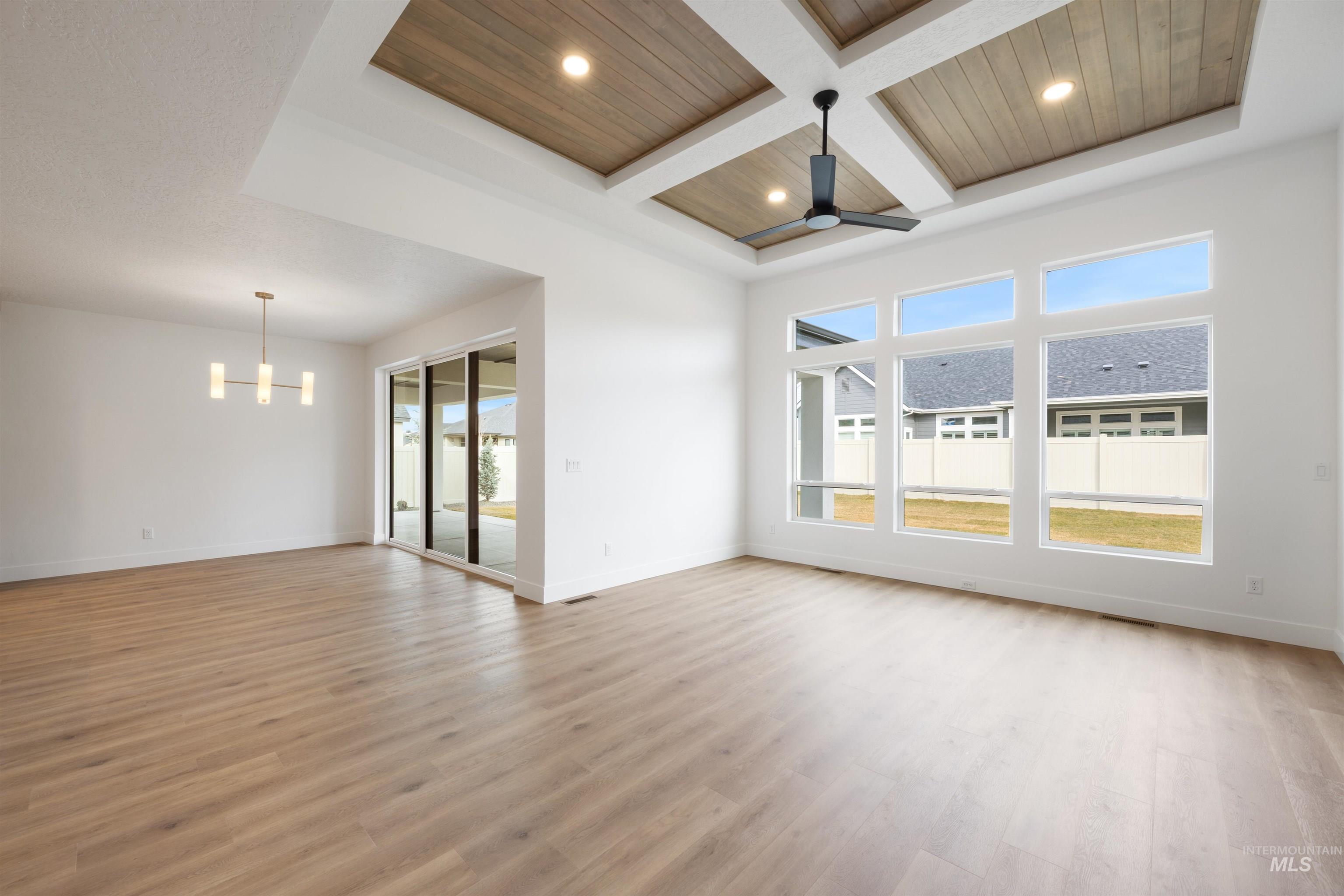 Unfurnished room with coffered ceiling, wooden ceiling, light wood-style floors, a chandelier, and ceiling fan