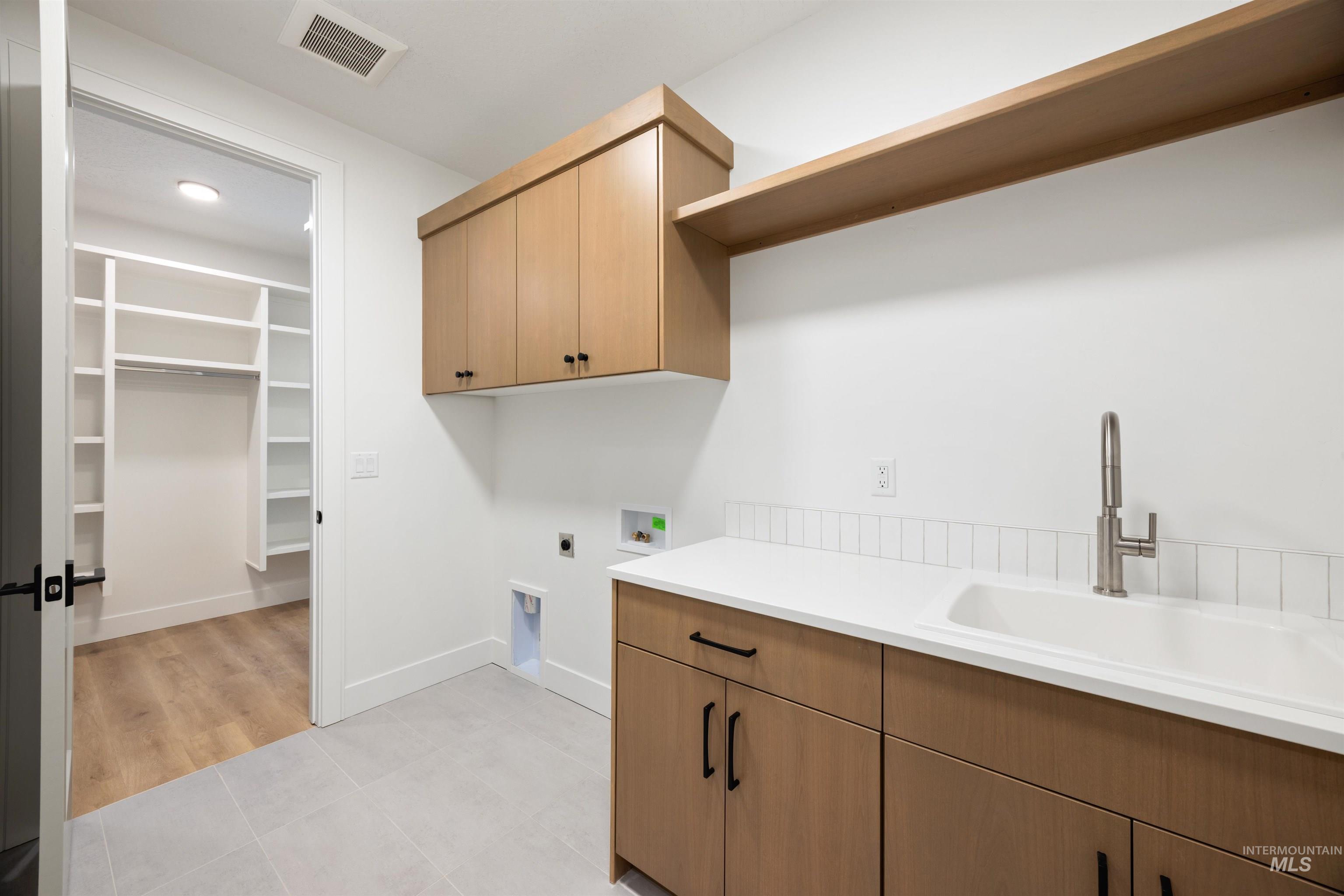 Laundry room featuring electric dryer hookup, light tile patterned floors, cabinet space, and hookup for a washing machine